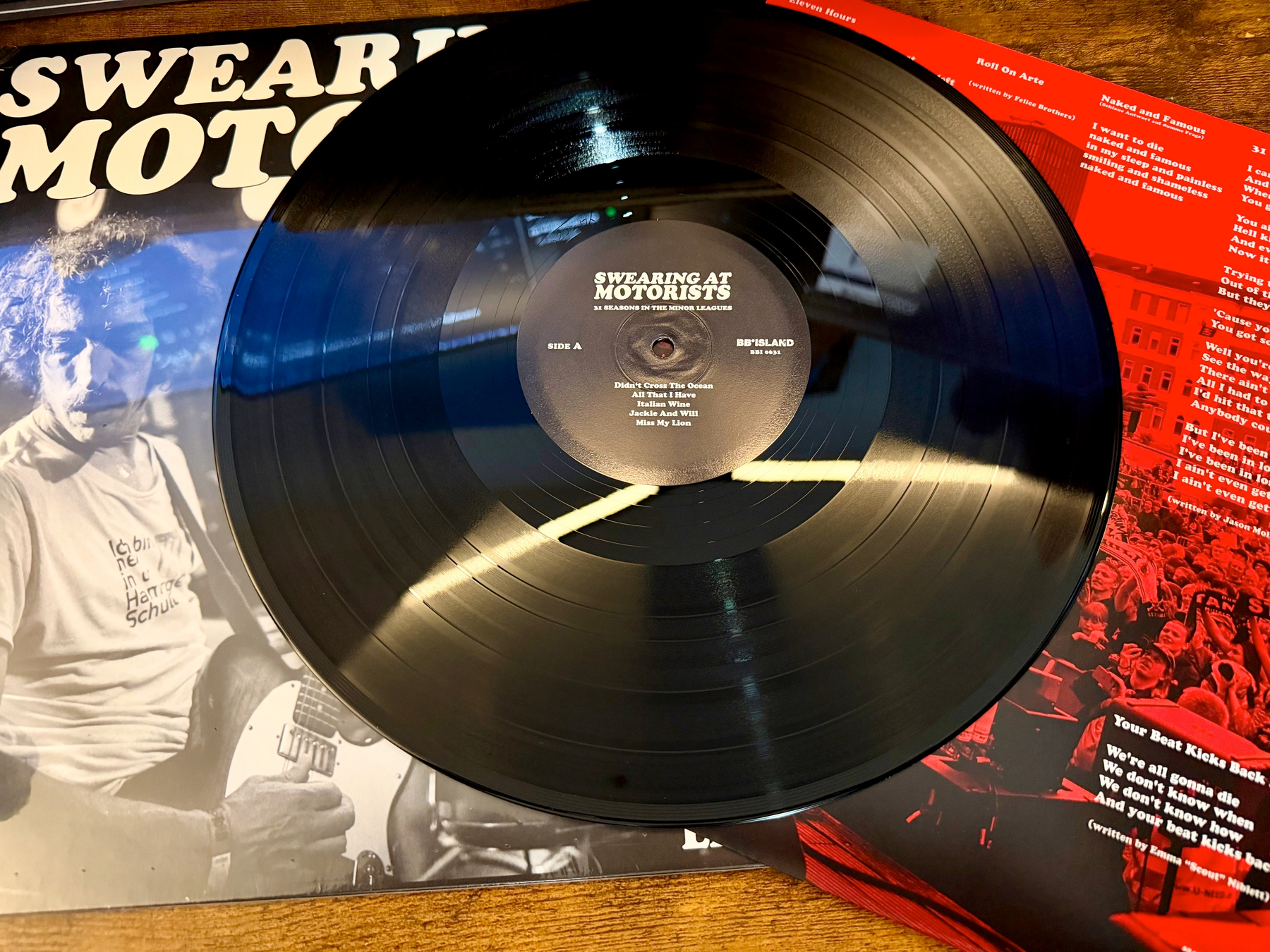 A black vinyl record from the album Swearing at Motorists is placed on top of its album cover and inner sleeve.