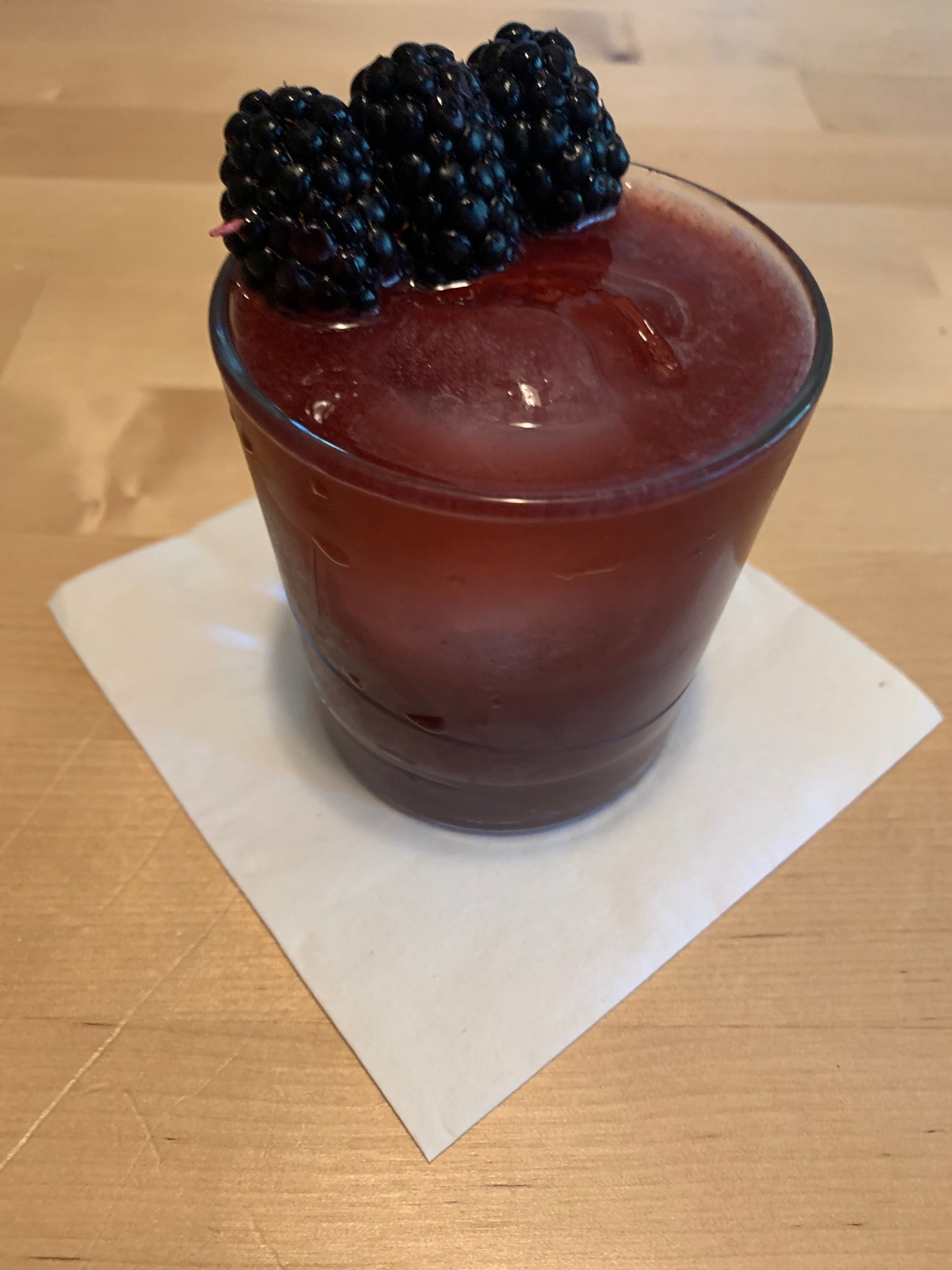 purple drink in a glass with ice and blackberries