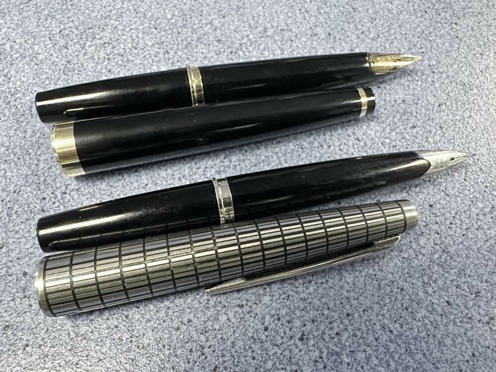 Two Pilot Elite fountain pens, uncapped. One black with gold trim. The other has a black barrel and silver/black cap.