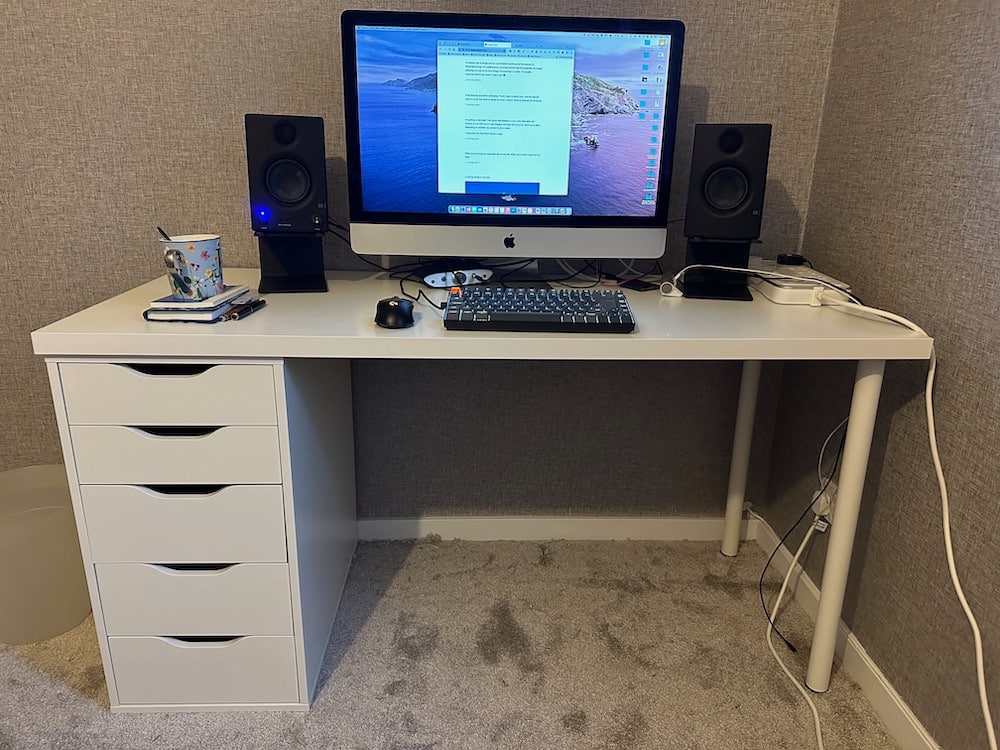 New white desk with iMac computer and speaker setup. 