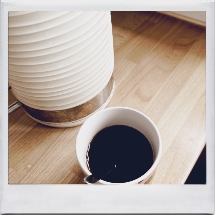 Mug of tea, and kettle, on counter top.