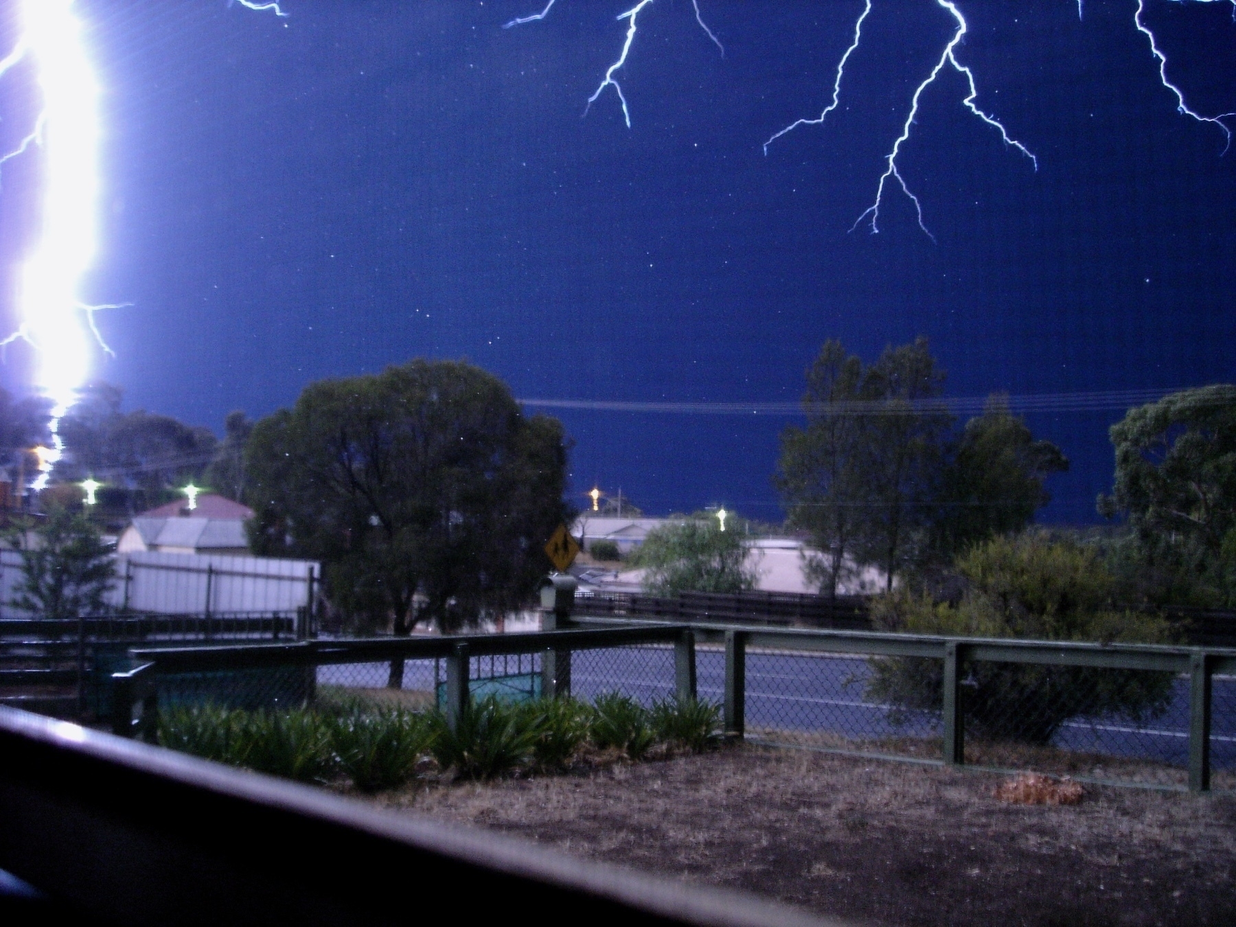 Lightning striking close to the ground near a surburban street. 