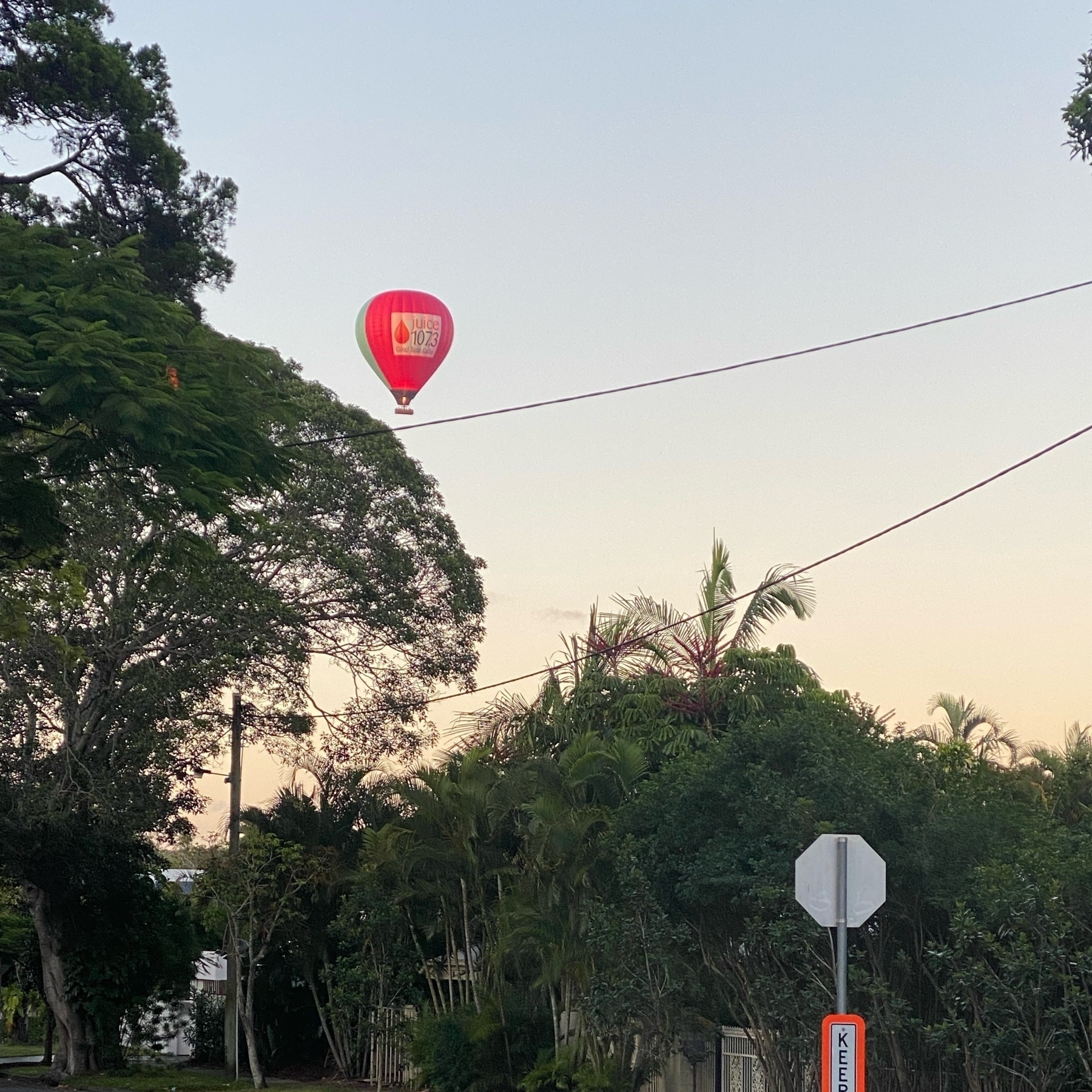 hot air balloon floating over a suburban street. 
