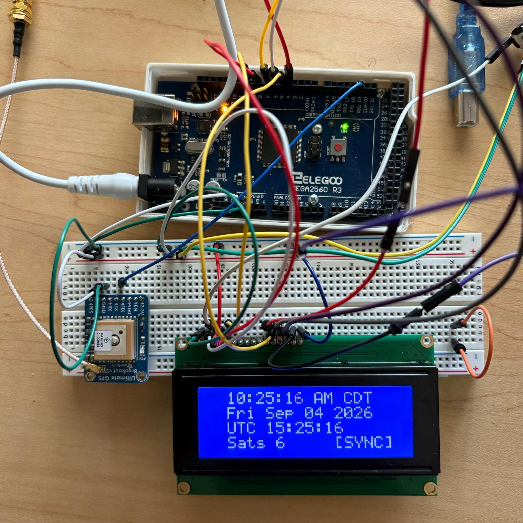 Arduino and breadboard covered with wires. An lcd display shows the time. 