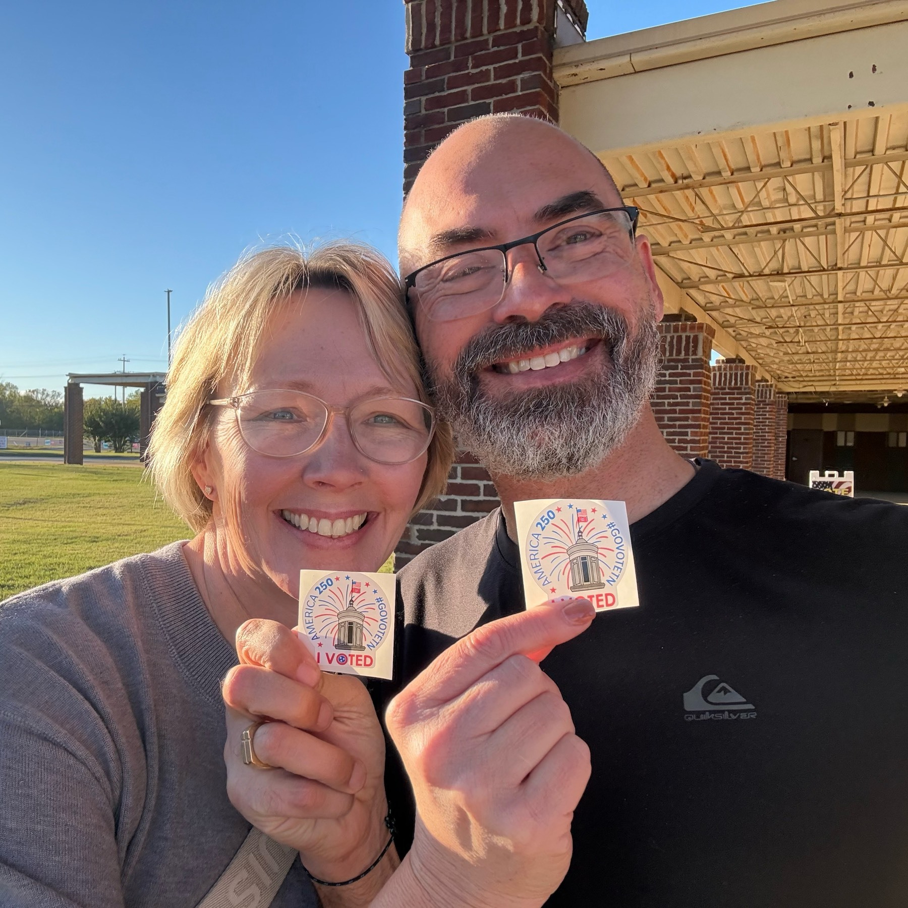 Self portrait with my wife outside our polling place and we're holding up "I voted" stickers 