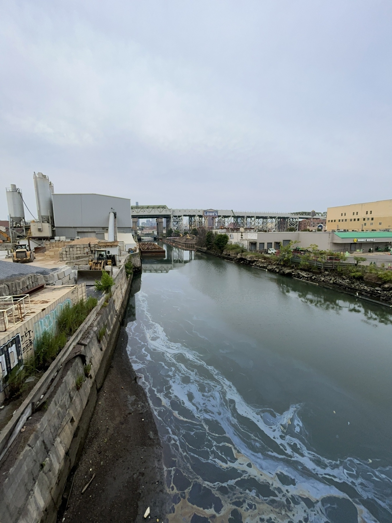 Oil slick on a canal with industrial buildings around it &10;