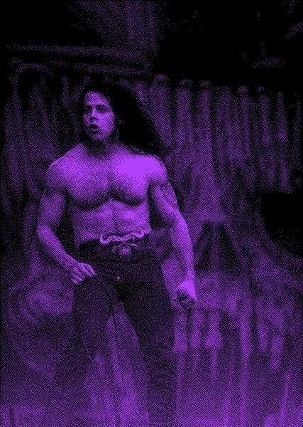 Grainy black and purple photo of Glen Danzig in the early 90s, shirt off, hair blowing, devil belt buckle.