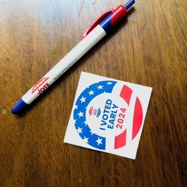 An "I Voted Early NYC 2024" sticker resting on top of a wood surface, along with the vote branded pen I used.