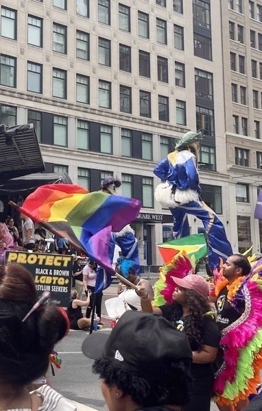 Two people in elaborate blue costumes and white masks do stilt walk dances.