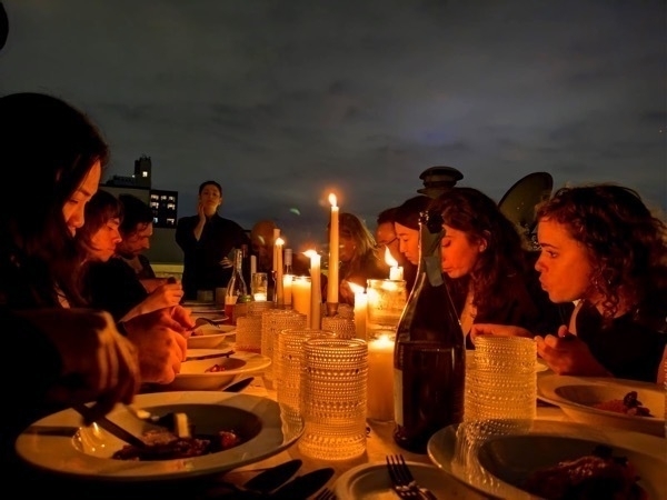 A group of individuals gathered around a table adorned with candles, creating a warm and inviting atmosphere.