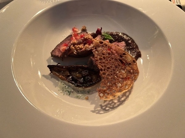 Close up of sliced duck and eggplant in a white plate.