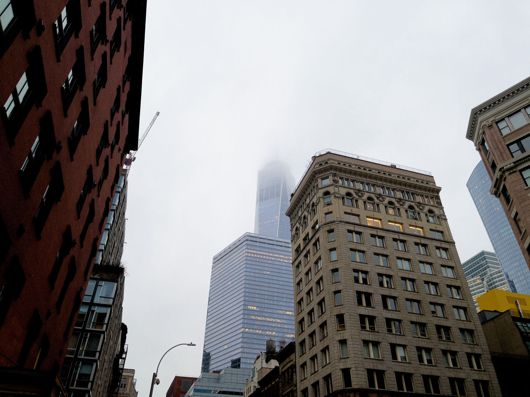 Auto-generated description: A view of tall buildings in a city with a foggy sky partially obscuring the top of a skyscraper.