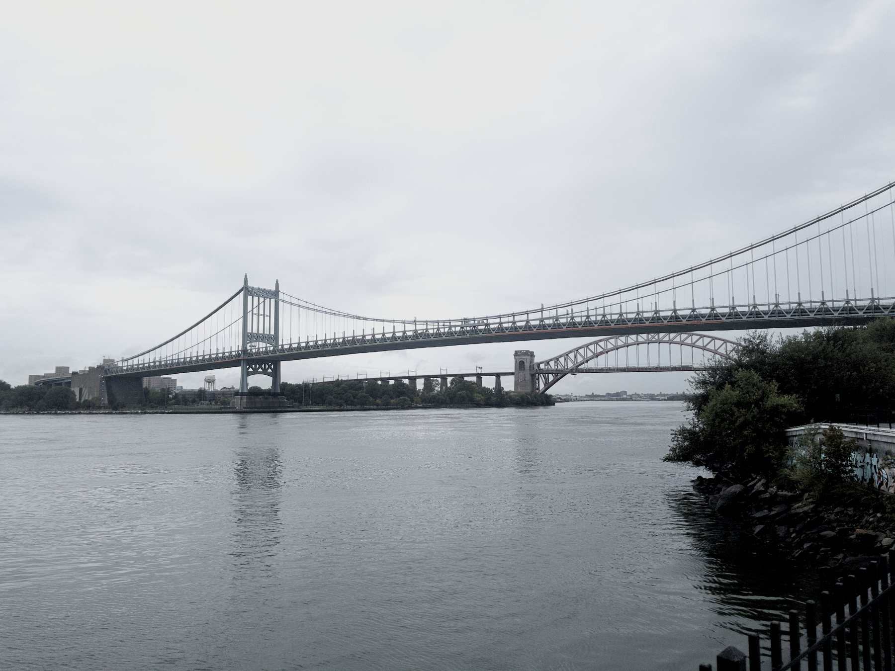 Auto-generated description: A scenic view features a large suspension bridge spanning across a calm body of water with trees along the shoreline.