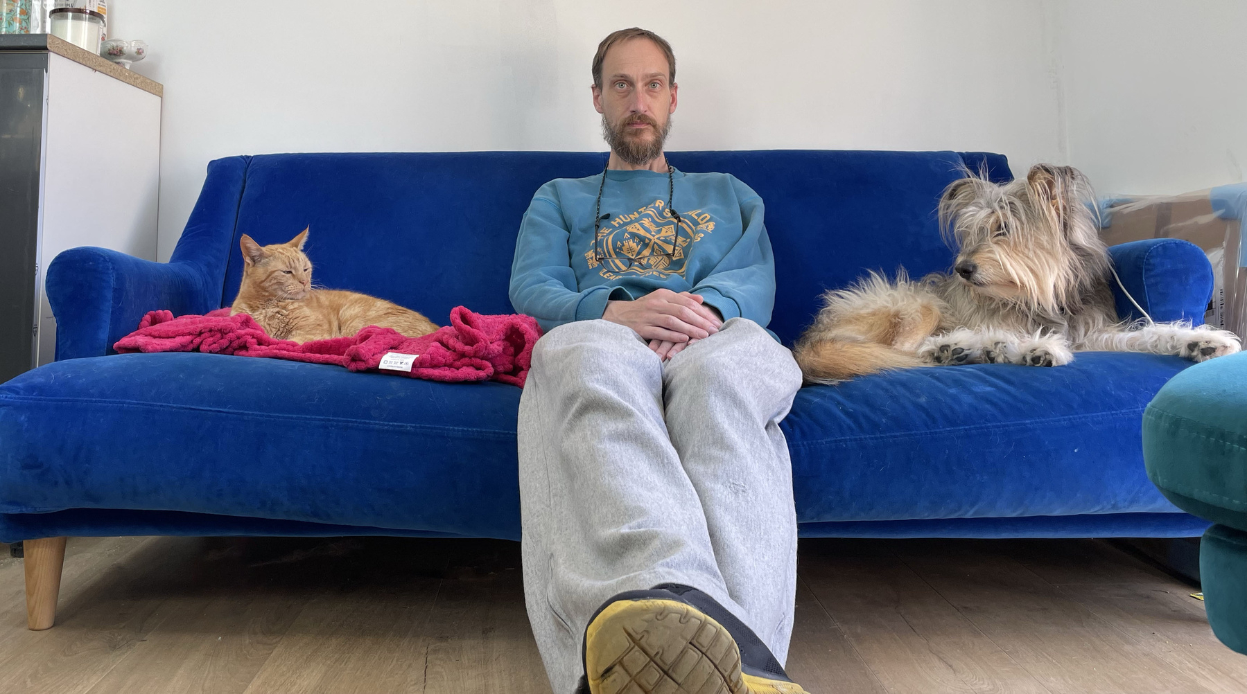 Dr. Adam Procter sits on his couch with his dog, Monty to his left and his cat Marmalade to his right, it resembles a photo for a nerd interview magazine, this is not a bad thing.