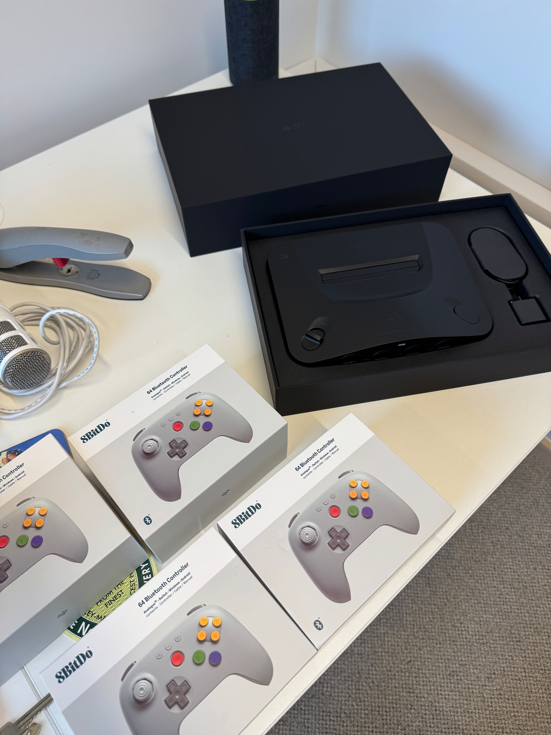 A set of 8BitDo controllers, an Analogue N64 console in a black box placed on a white table.