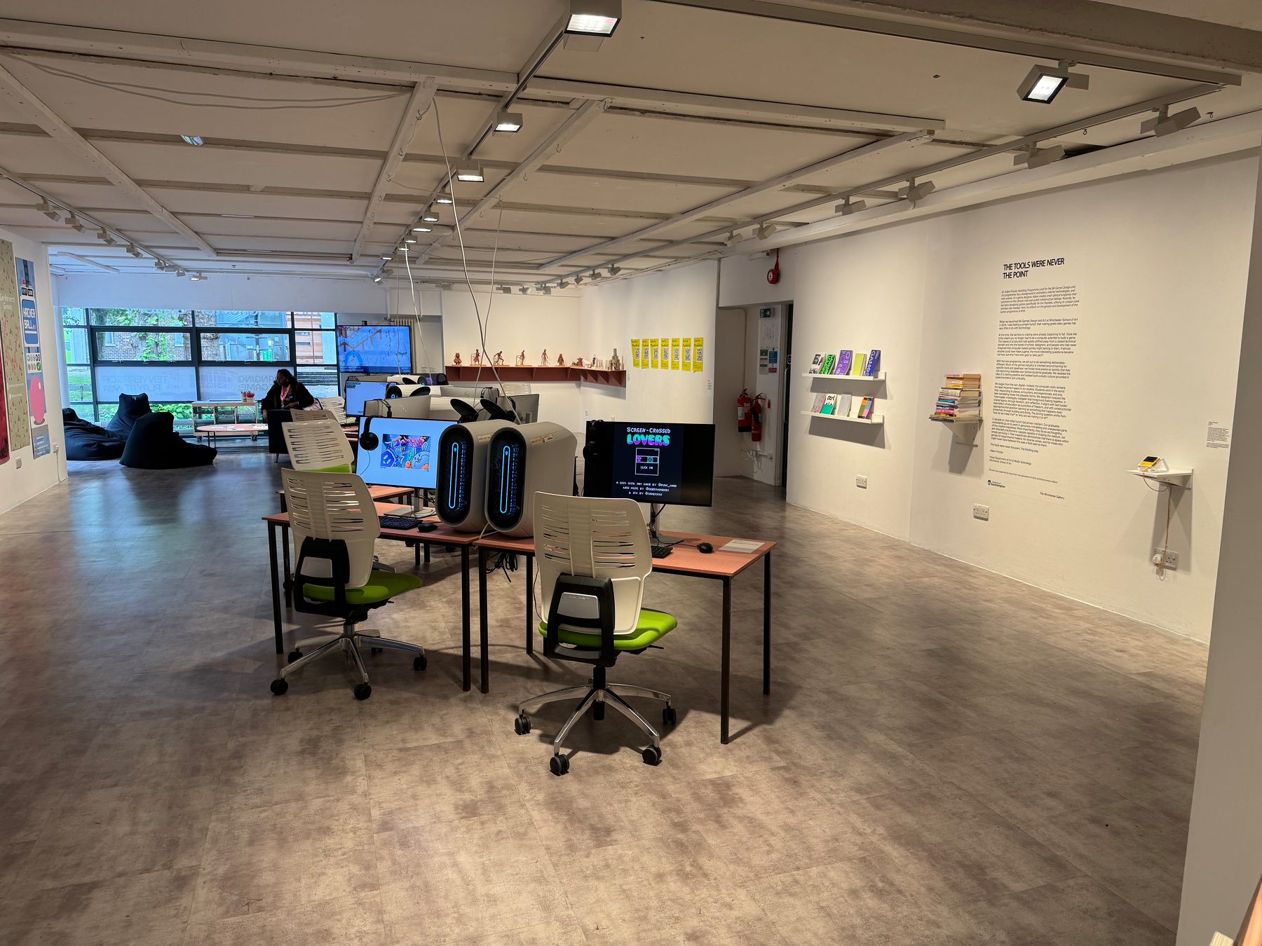 A modern, spacious room with computer workstations, art displays on the walls, and seating areas.