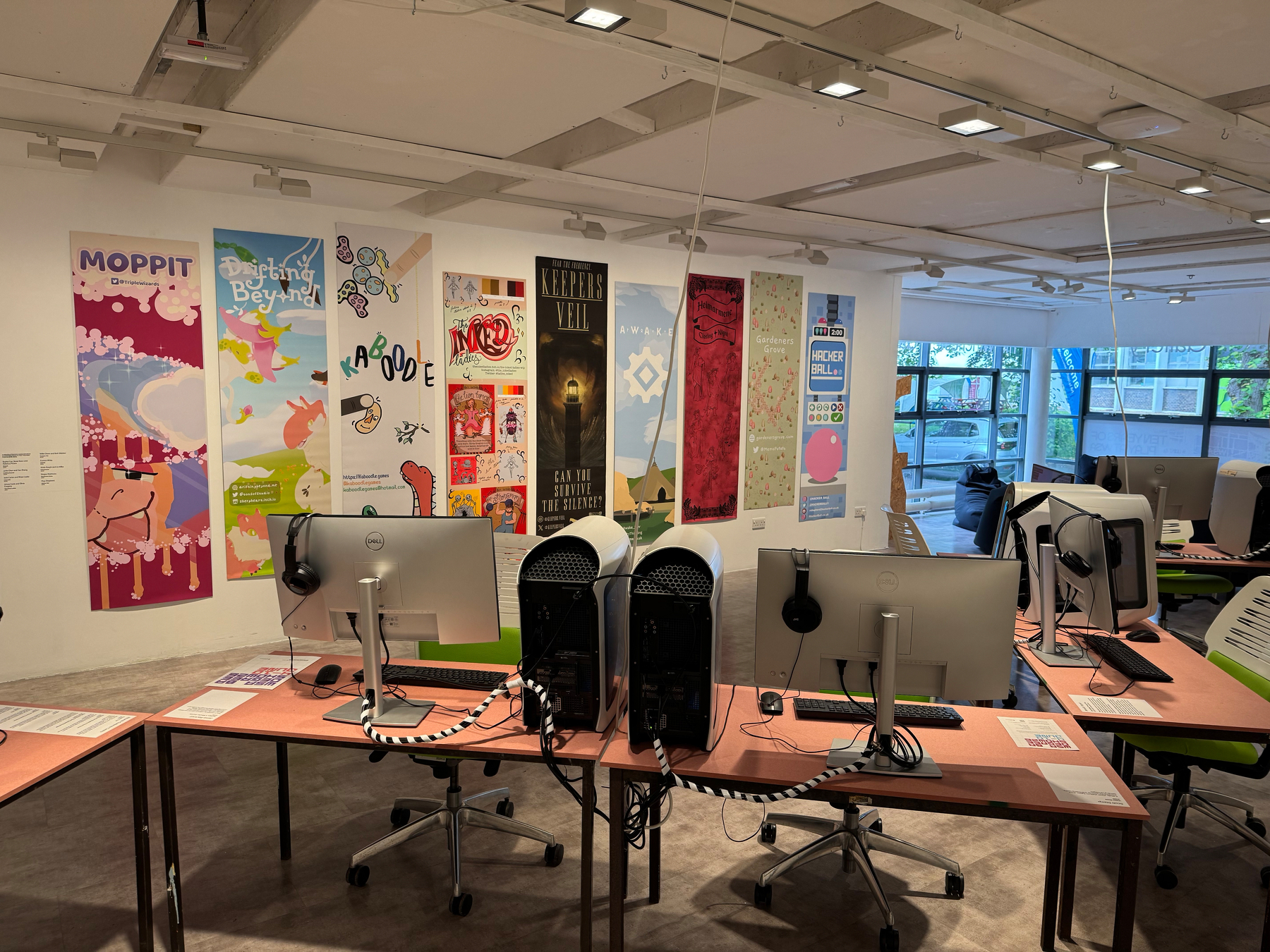 A computer lab with several workstations is decorated with colorful posters on the back wall.
