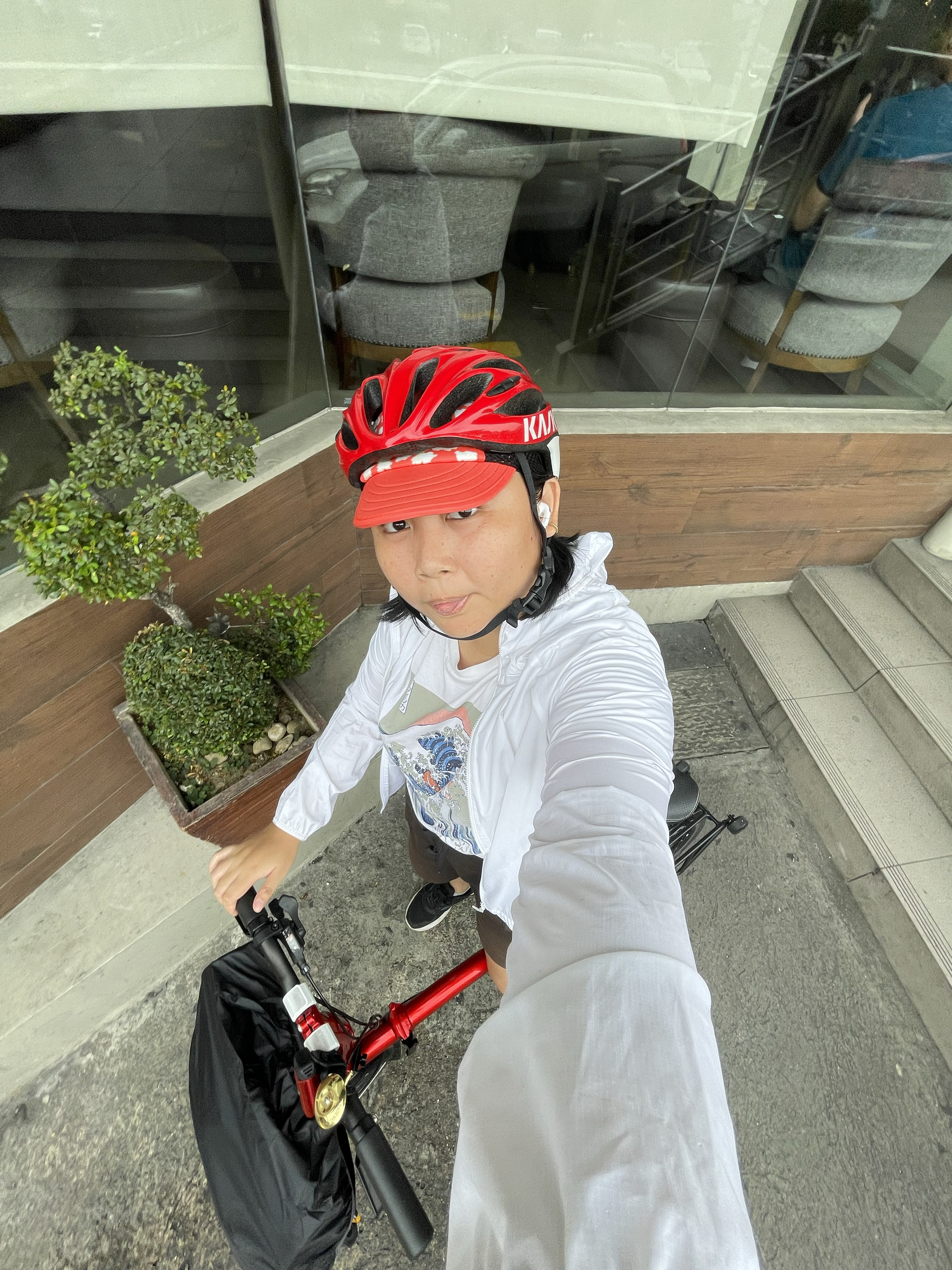 wide-angled selfie of Chi in her bike commute attire, with her cycling cap and helmet combo, plus her water resistant jacket for rainy rides.
