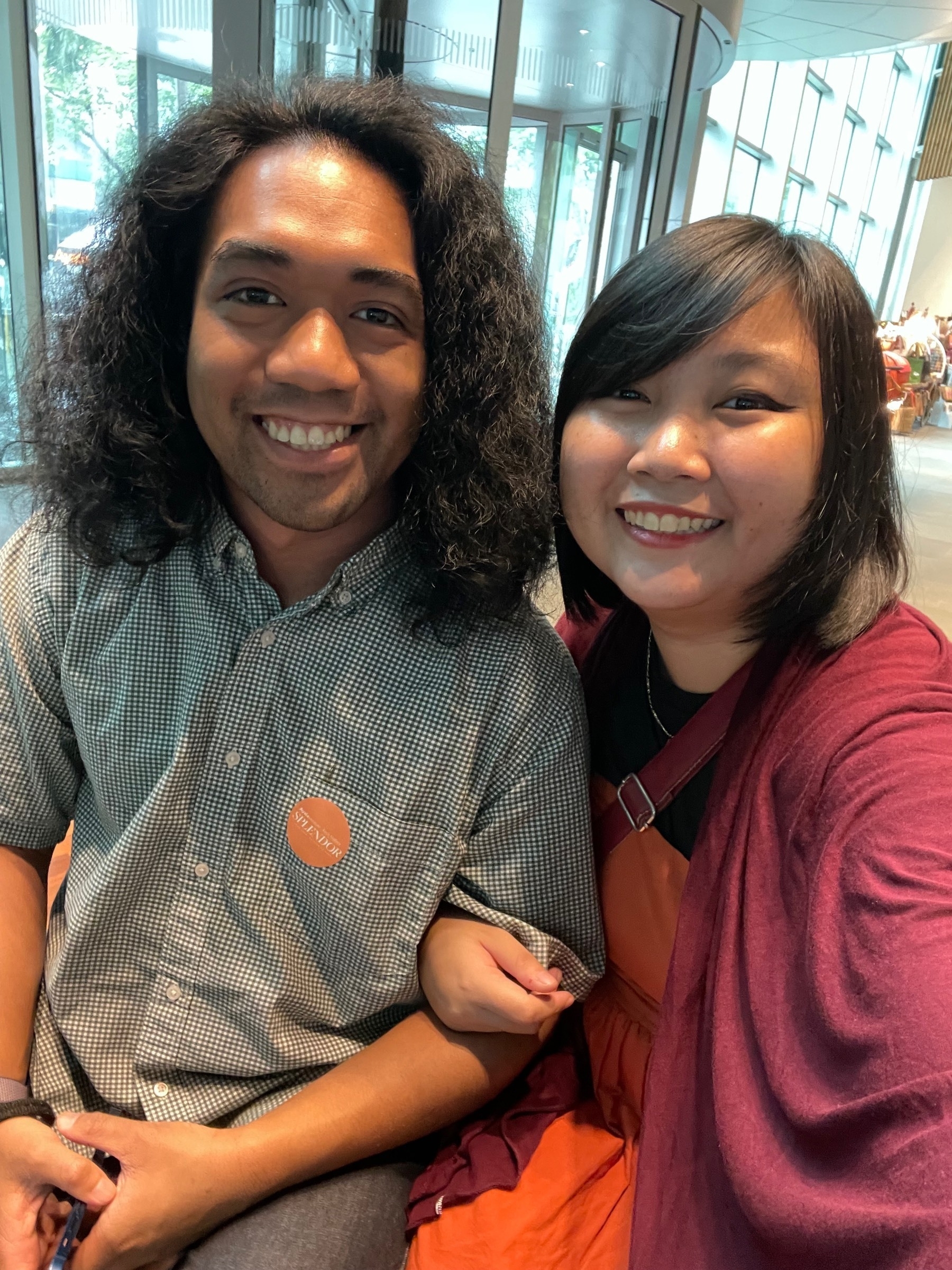 Selfie of Chi and Richard, her boyfriend, together at the lobby of Ayala Museum for a date. Richard has a "SPLENDOR" orange sticker on his right chest pocket, which is the museum's way of identifying visitors for the Splendor exhibit. Chi's hand is wrapped around Richard's, with her other hand off camera, holding the phone to take the photo.