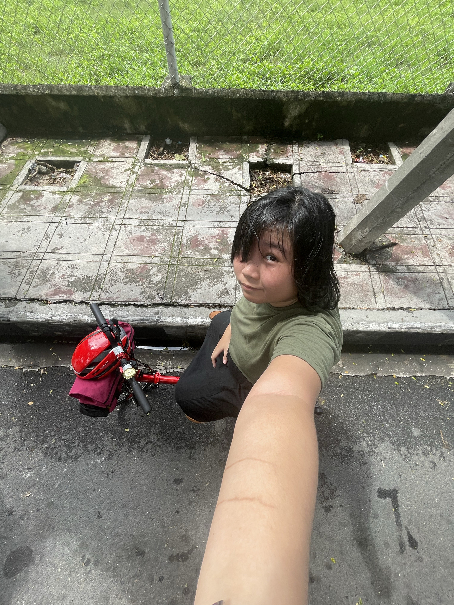 wide angled selfie of Chi on her trifold bike while waiting on the side of the road