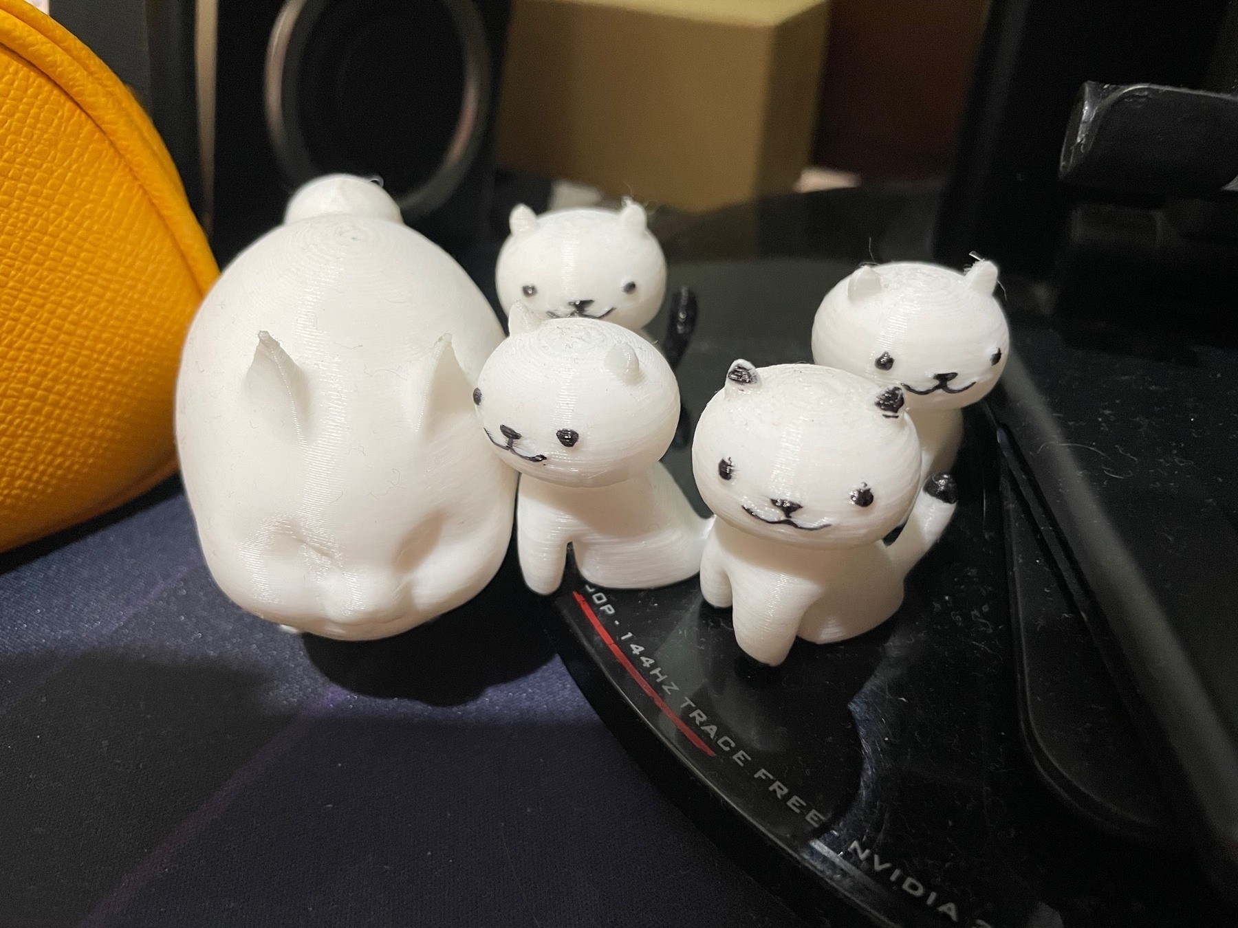 Chi's 3d-printed cats, given to her by her boyfriend. She has one big fat cat, which is based on the fat cat in FFXIV, and 4 smaller Neko Atsume style cats that have their eyes, nose, mouths, and some patterns colored in with a black marker.