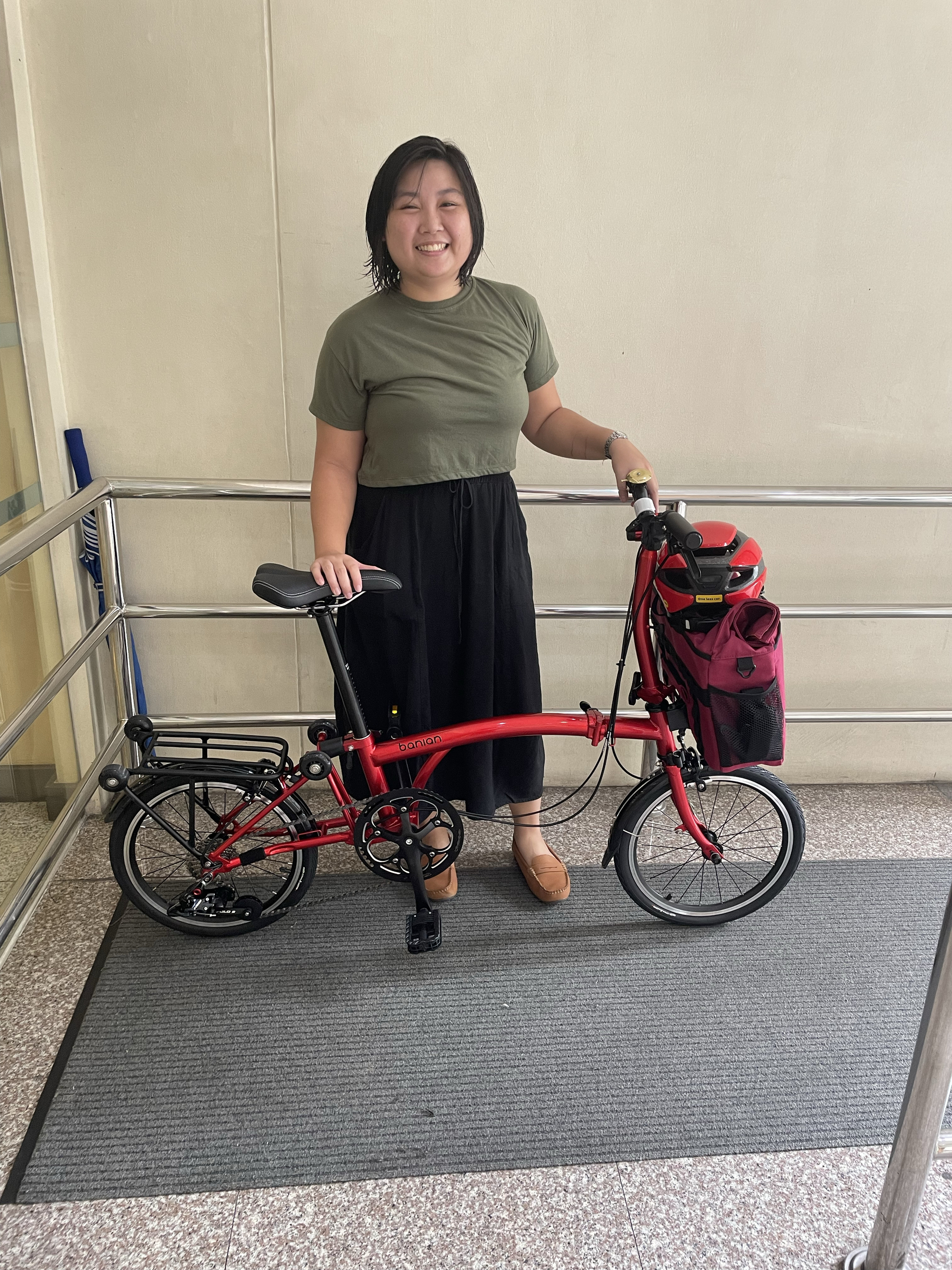 photo of Chi with her red trifold bike, showing her outfit and her bike commute setup