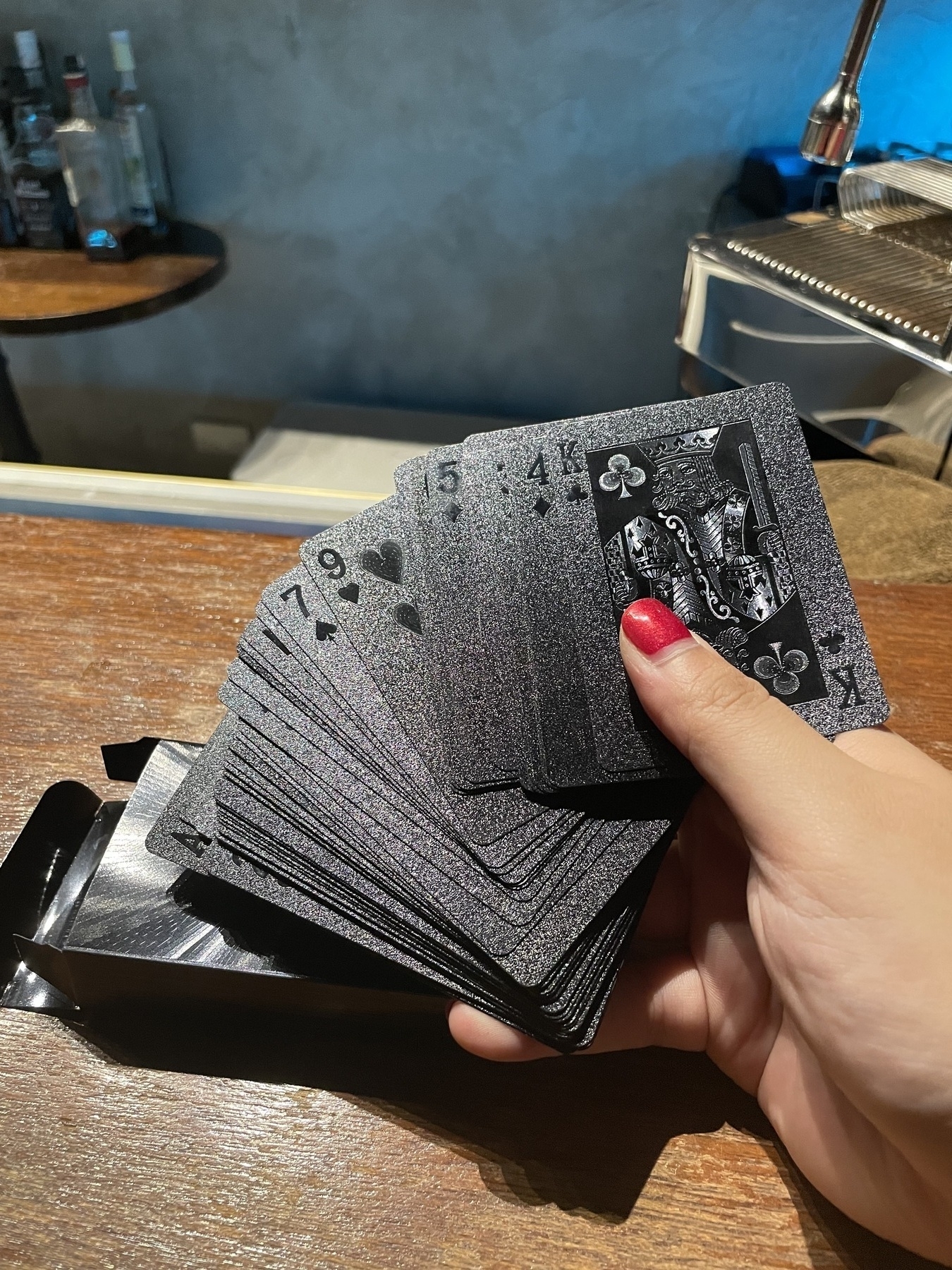 Chi is holding a deck of cards partially fanned out in her right hand. The cards themselves have a sheen texture, with the faces or symbols of each of the playing cards just a darker black to make it obvious when light shines on the surface of the card.