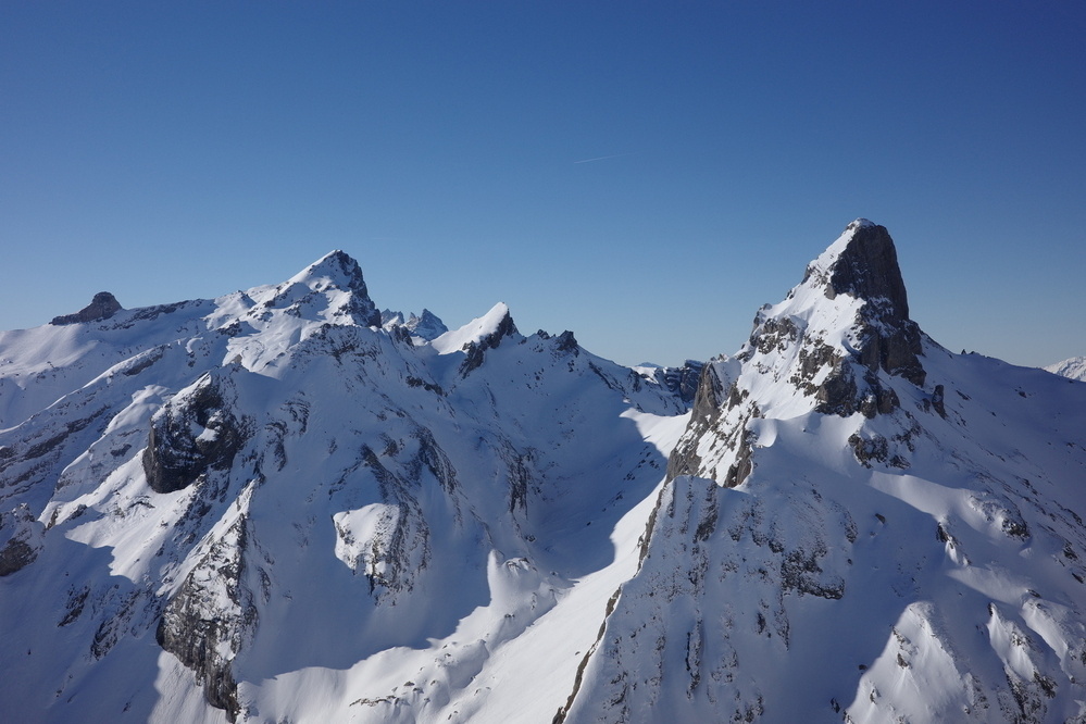 Snow-covered mountain peaks rise sharply under a clear blue sky.