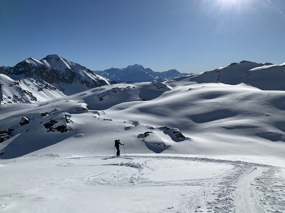 A person is skiing on a snowy mountain landscape under a clear blue sky.