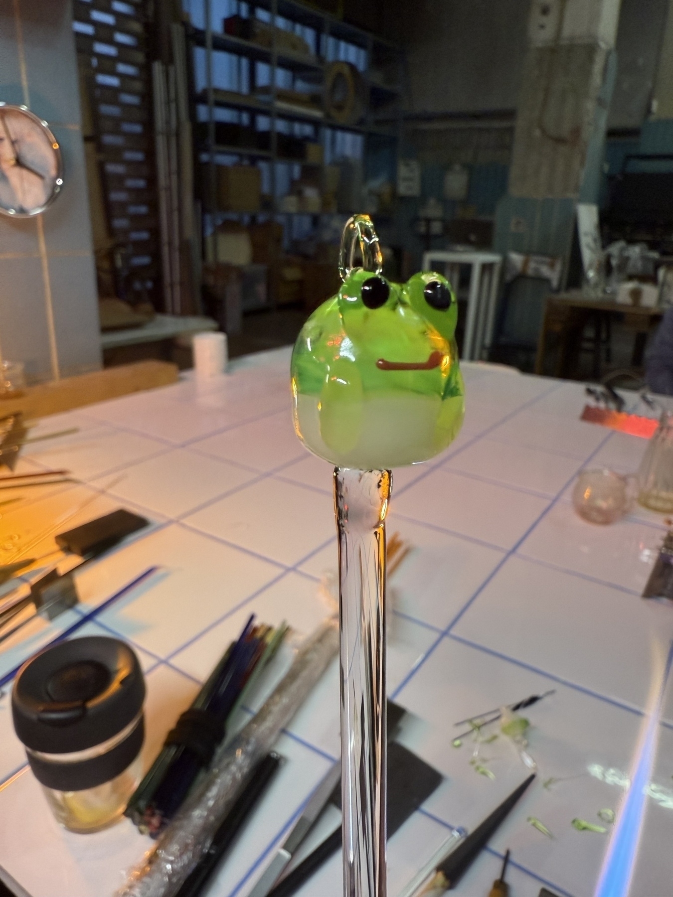 A very cartoon looking frog made of glass on the end of a clear punty.