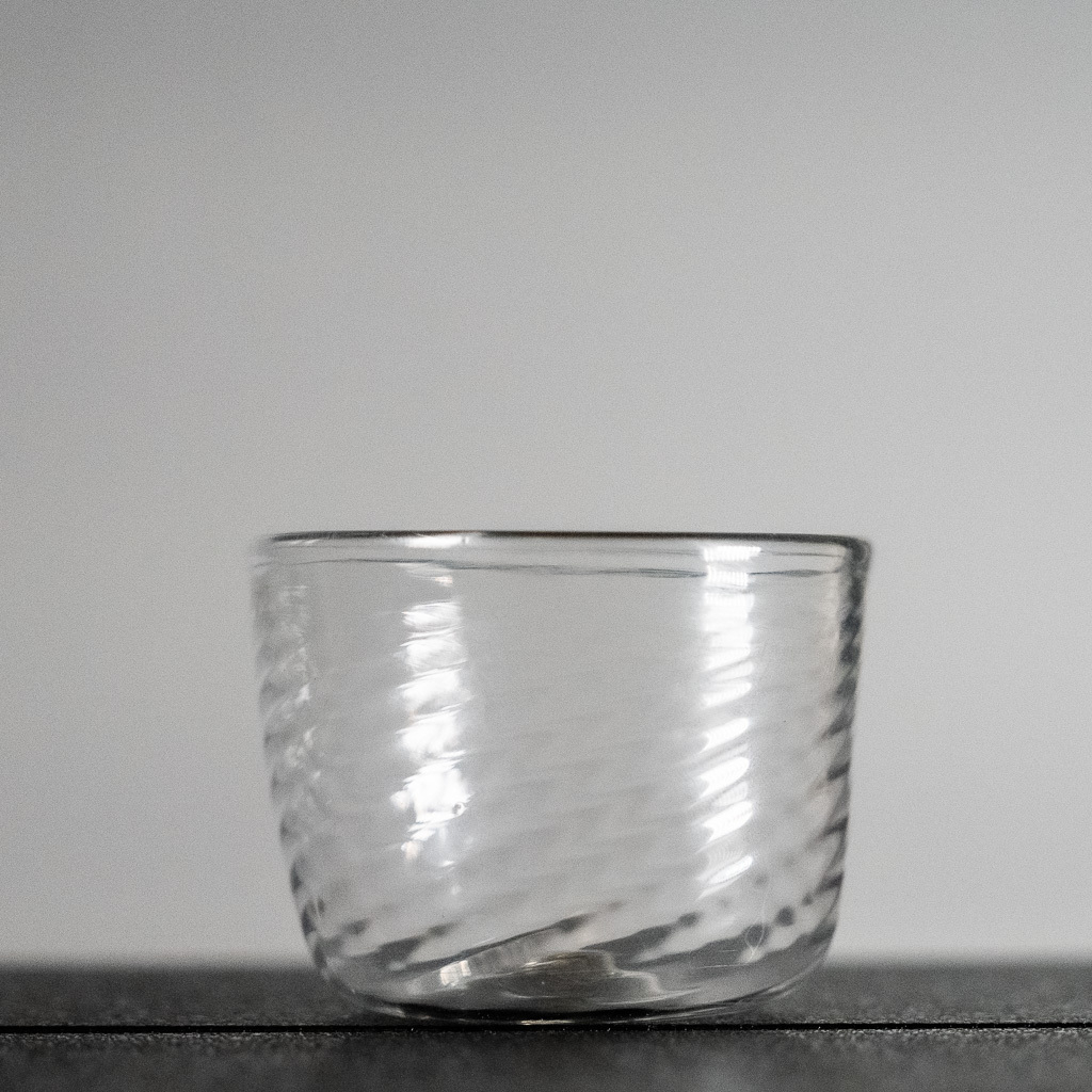 A small but level cup. It has optic ridges twisted into the walls. The sides are not _quite_ even.