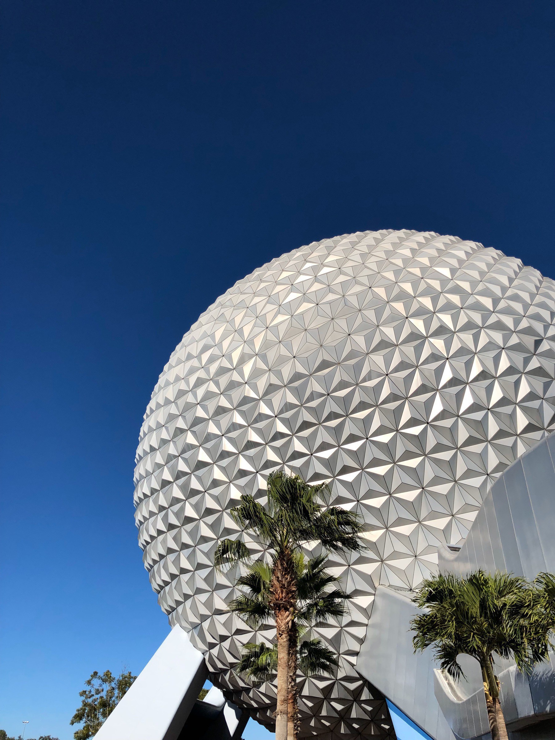 A shot of Spaceship Earth showing in the right-hand side of the photo against a brilliant blue sky.