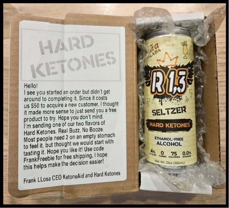 A picture of an open package containing a can of the KetoneAid drink and a note taped to the inside of the box top that says: Hello! I see you started an order but didn't get around to completing it. Since it costs us $50 to acquire a new customer, I thought it made more sense to just send you a free product to try. Hope you don't mind. I'm sending one of our two flavors of Hard Ketones. Real Buzz, No Booze. Most people need 2 on an empty stomach to feel it, but thought we would start with tasting it. Hope you like it! Use code FrankFreebie for free shipping, I hope this helps make the decision easier! Frank LLosa CEO KetoneAid and Hard Ketones