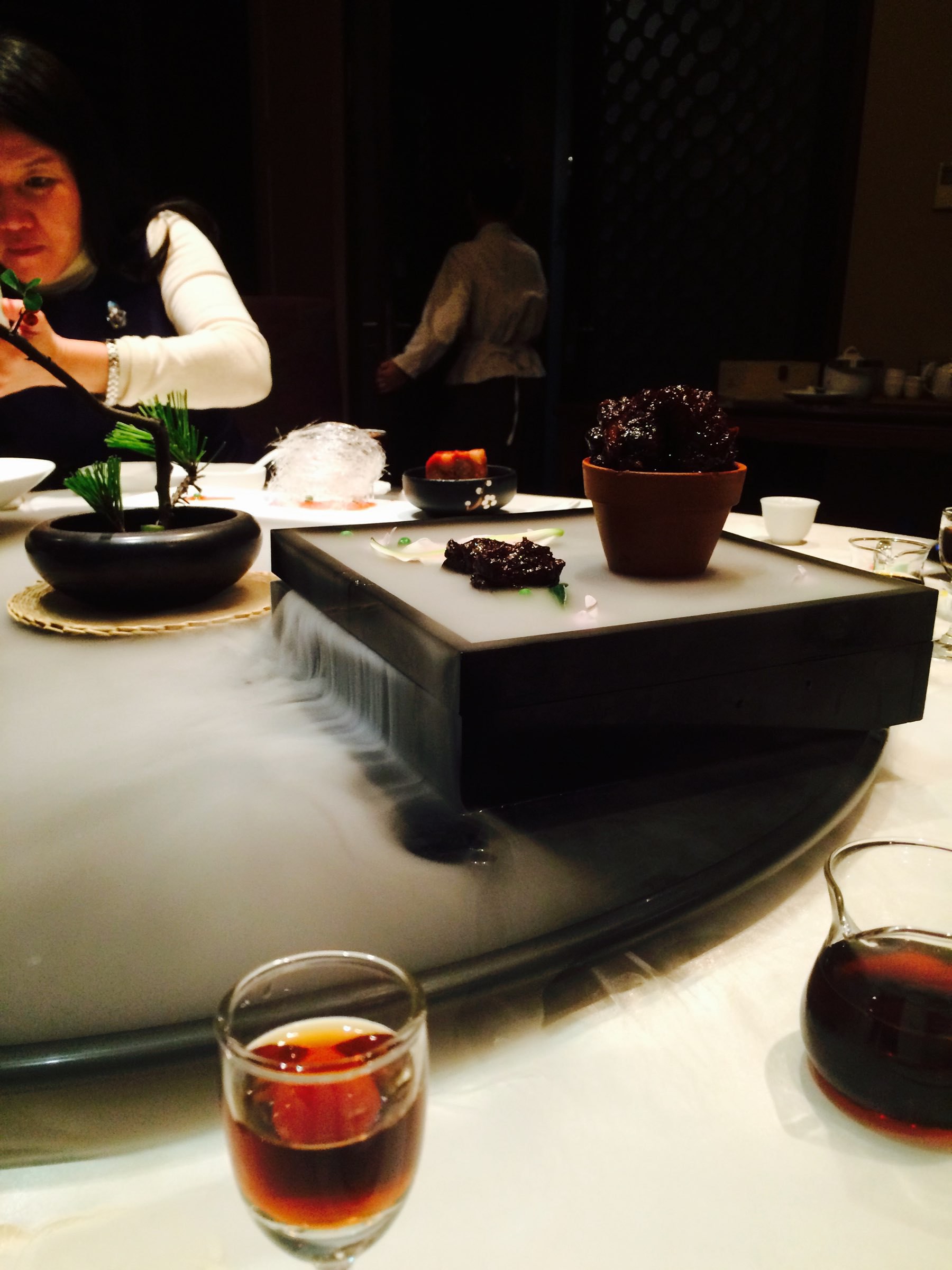 Chinese restaurant. Foreground: licquor in a glass. Further back: pork on a plate oozing dry ice