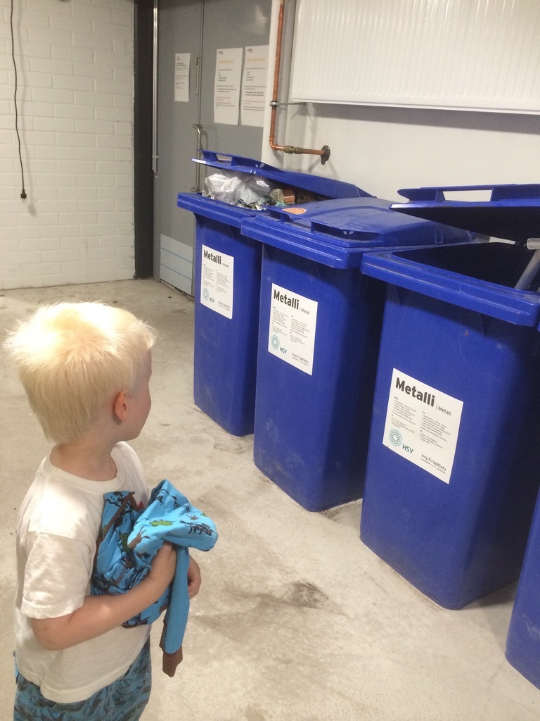 small boy and several trash cans in a concrete wall basement