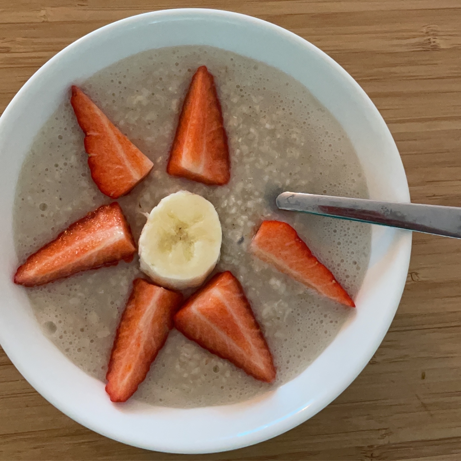 porridge with strawberries laid down in flower shape with a slice of banana in the middle