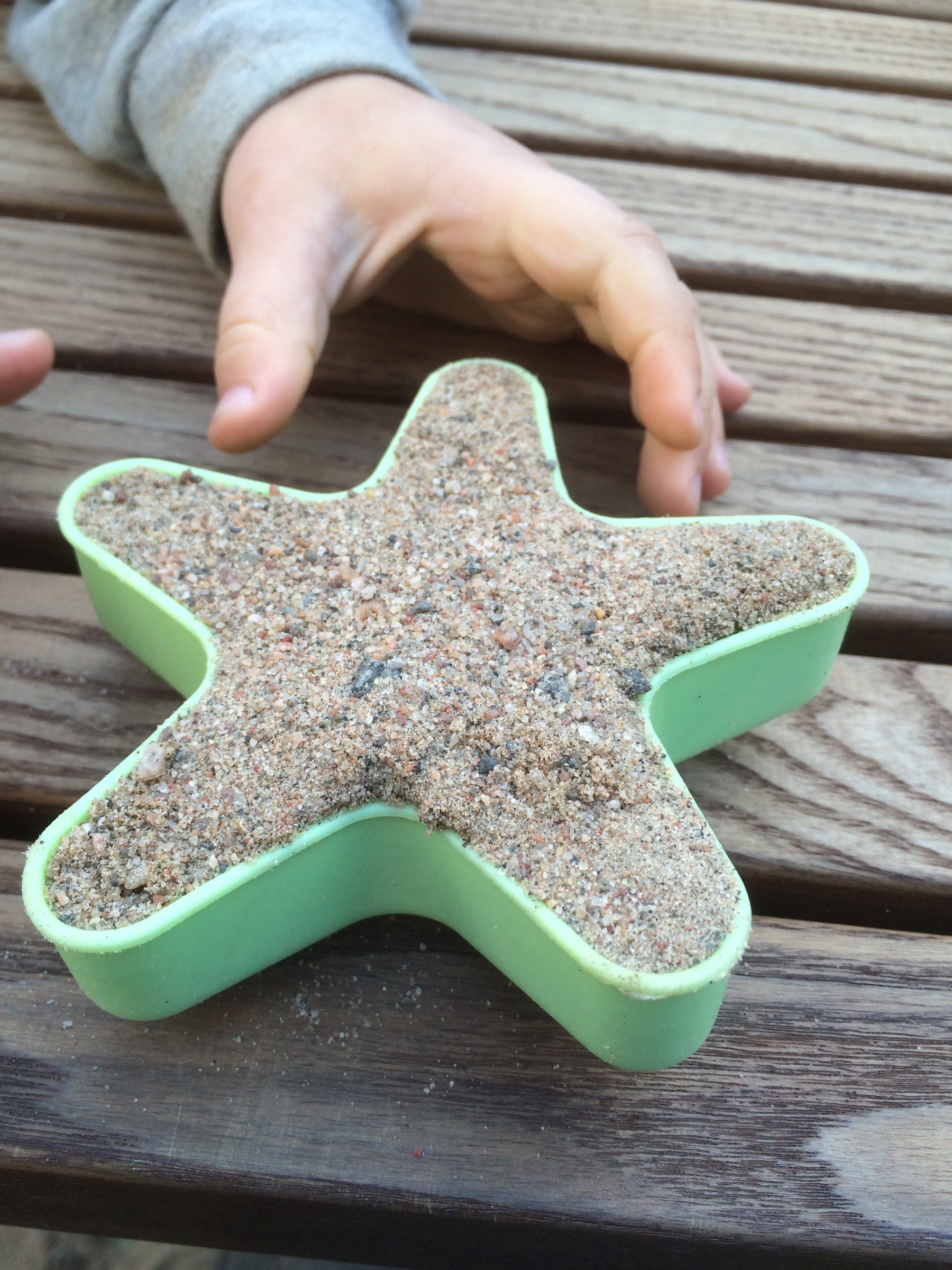star shaped mold full of sand. delicious looking sand cake and a hand