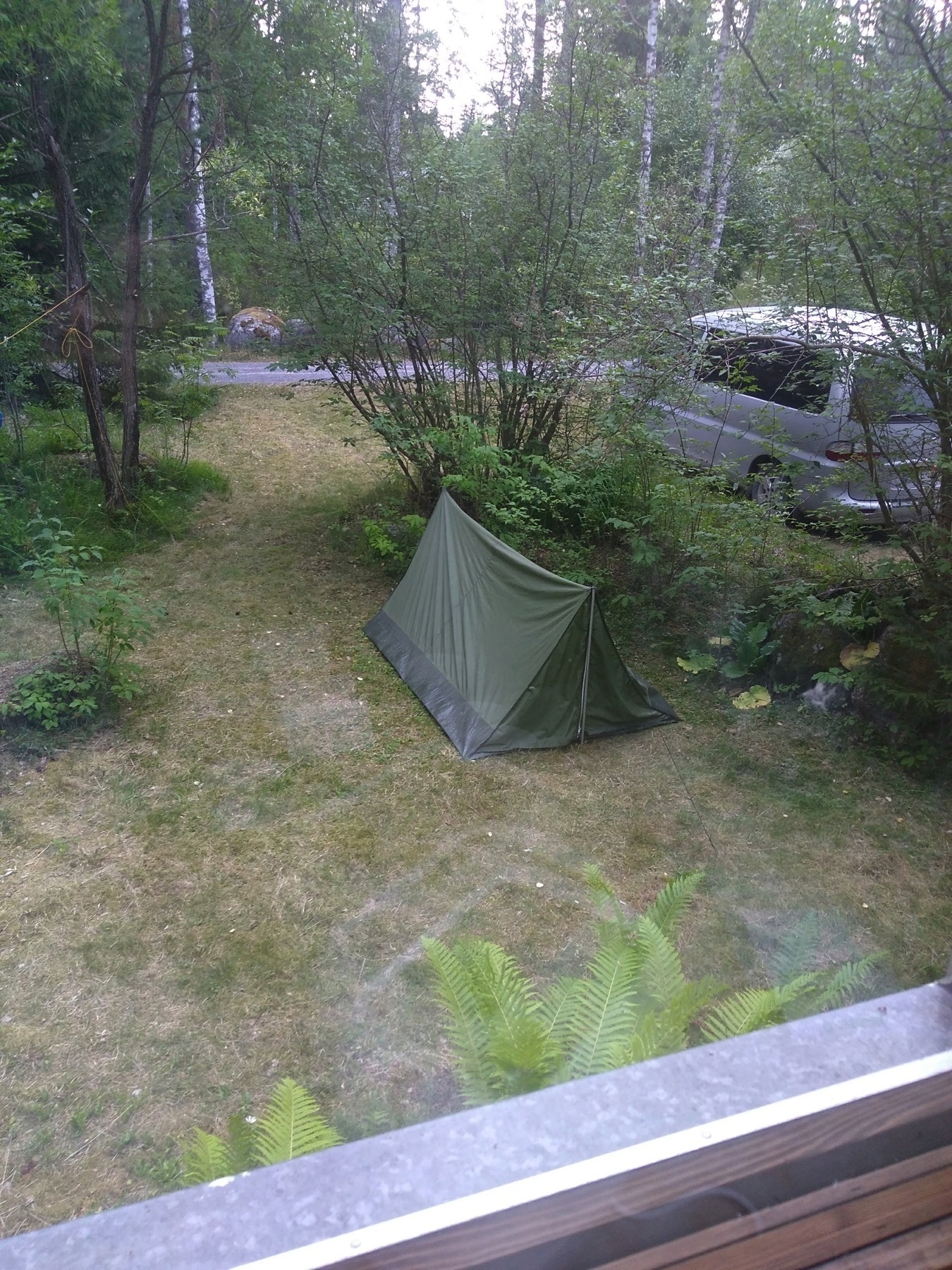looking out from the window, a tent, a van, grass and some bushes in the garden