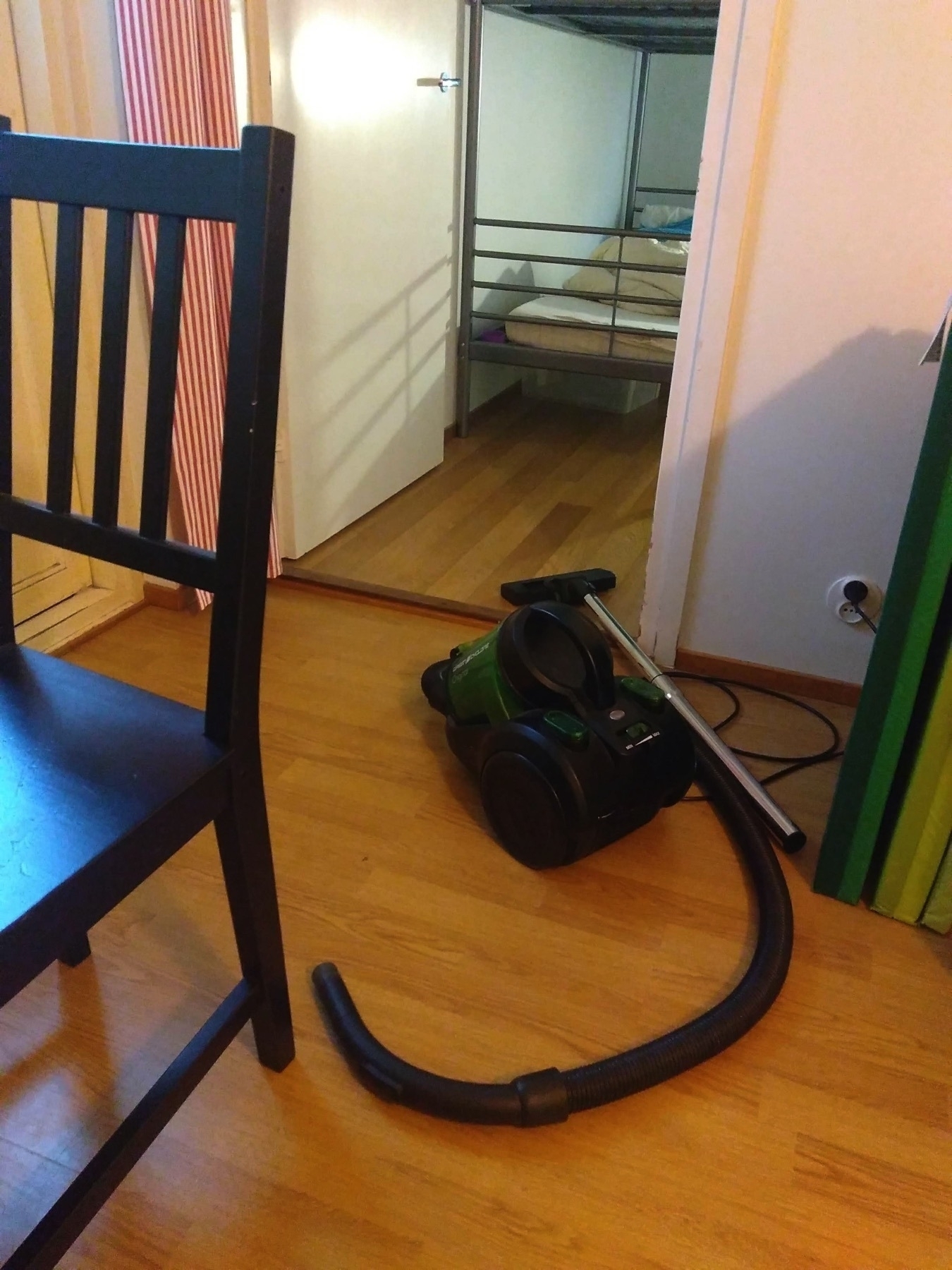 chair, vacuum cleaner, a bunk bed seen through an open door