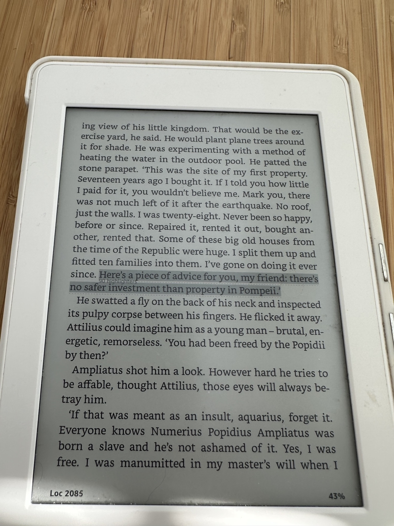 a picture of a kindle reader. Book "Pompeii" open on a page containing a highlight "Here's a piece of advice for you, my friend: 'there's no safer investment than property in Pompeii'