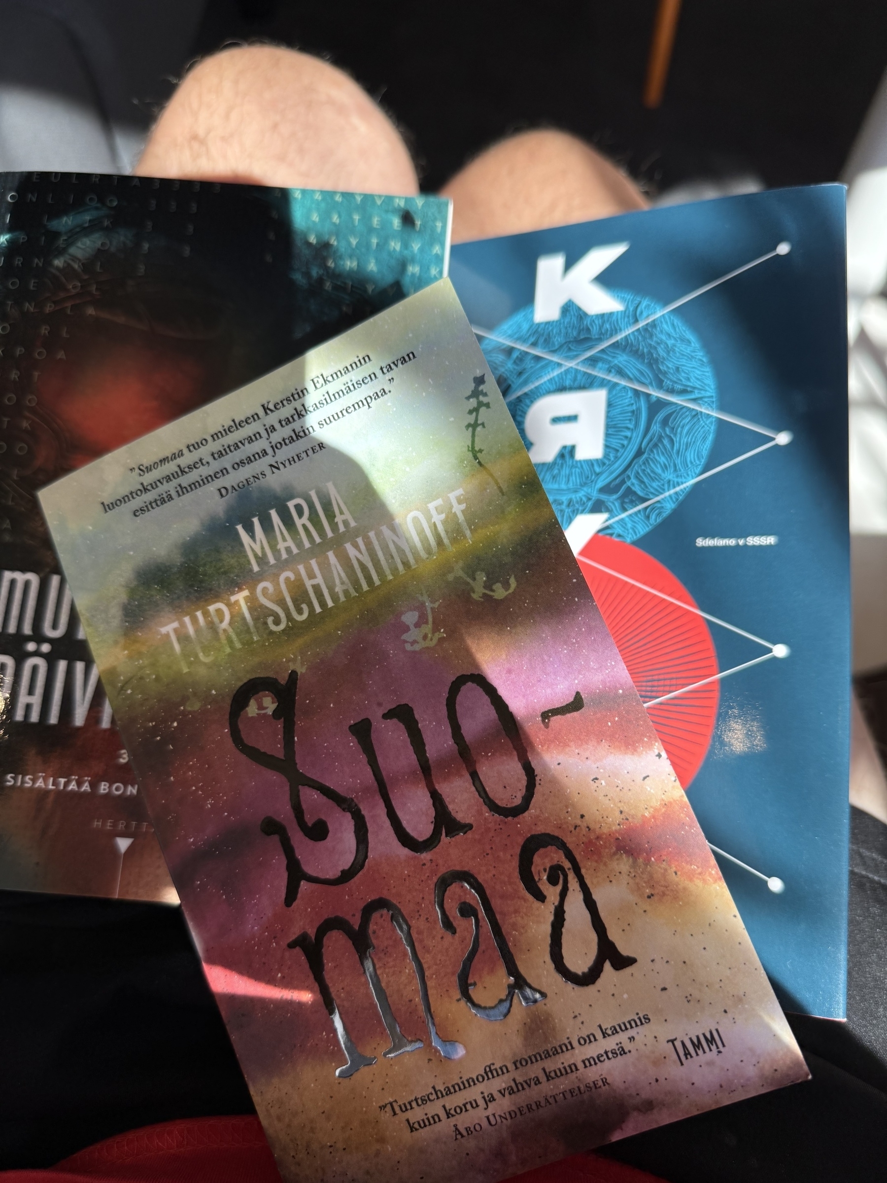 Three books on my lap and my knees&10;&10;Suomaa by Maria Turschaninoff&10;Krysa by Sami Tissari&10;Murdebot Diaries part 3&4
