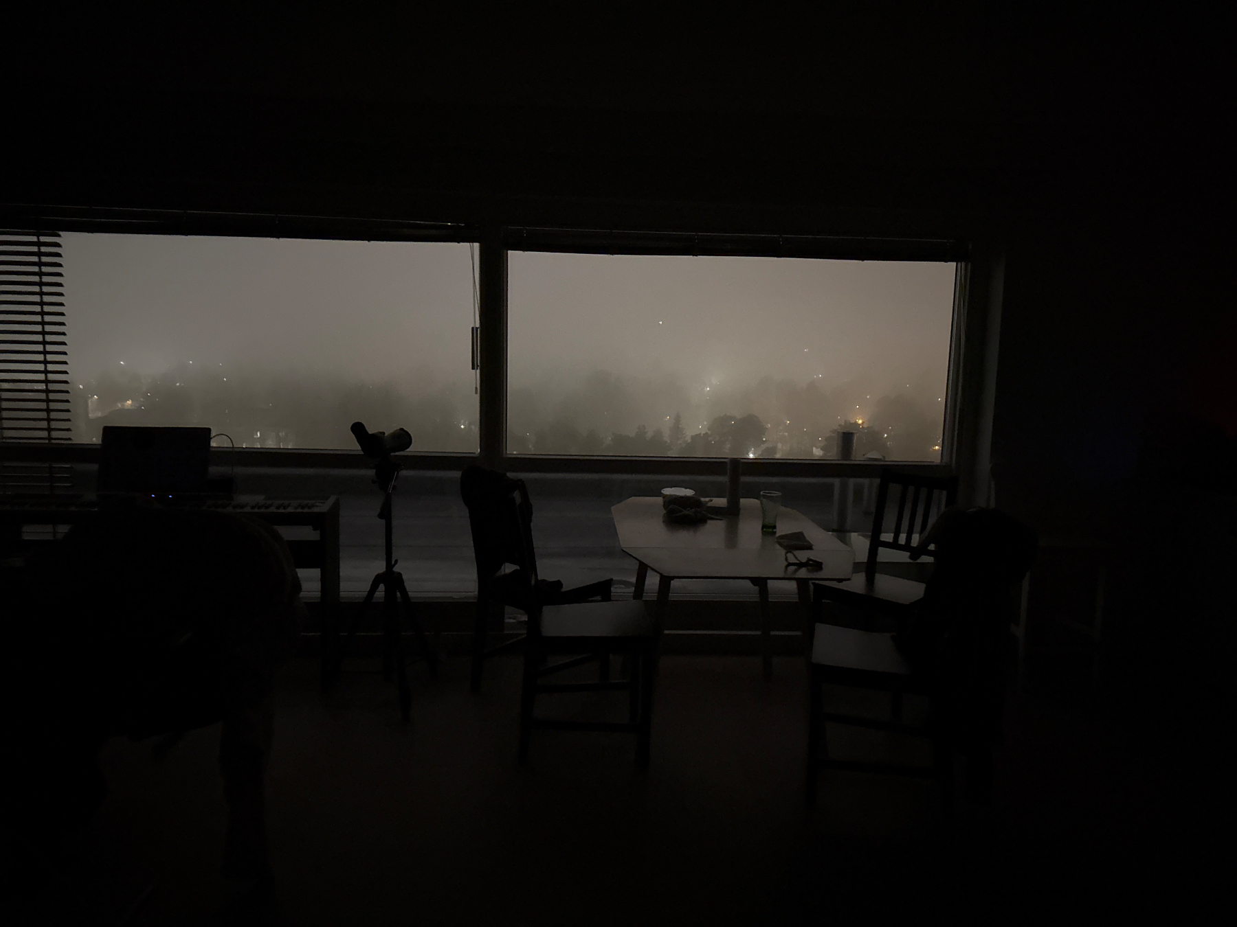 View out of my kitchen/living room window. The faint light coming from streetlights show glimpses of my furniture. Street lights peek through fog they were old stars