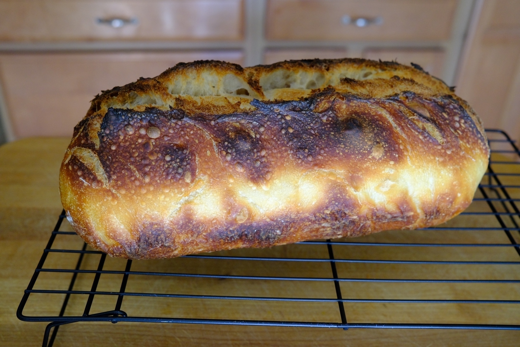 well caramelized sourdough loaf on a rack.