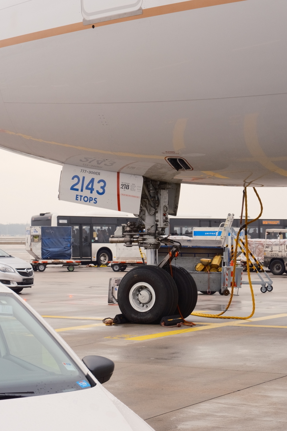 Front nose gear of the 777 with the aircraft ID of 2143. A bus is driving off on the background.