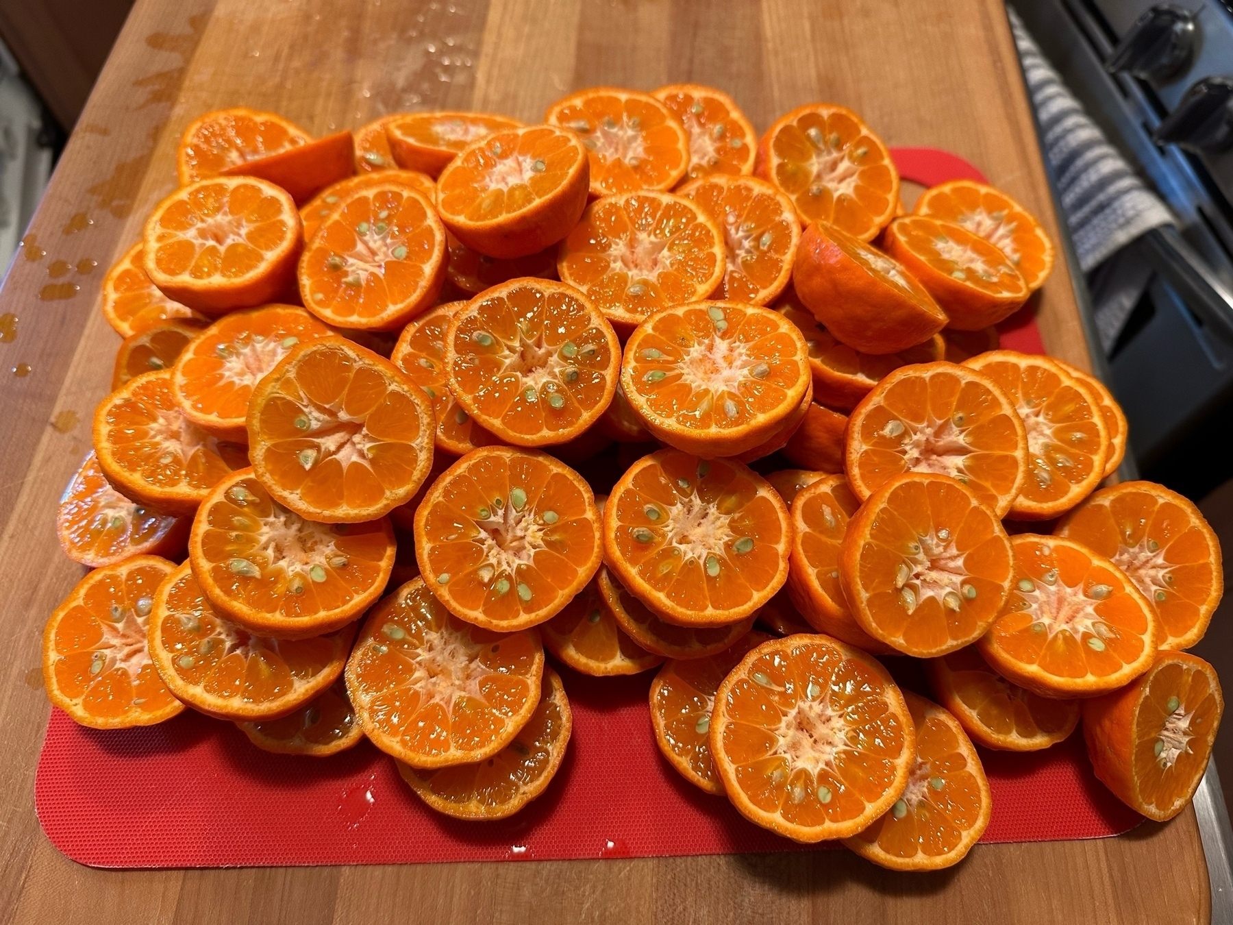 a pile of halved mandarins, cut side up, on a red cutting board.