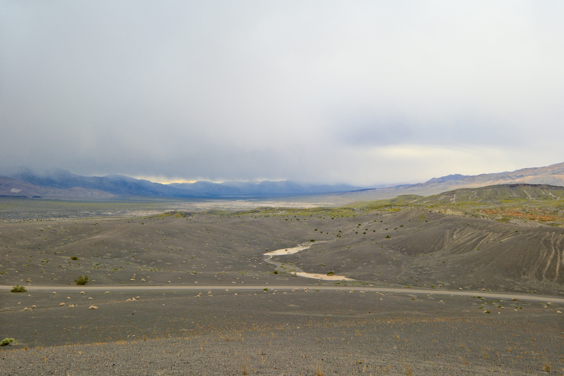 DSCF5436.jpg A wide-angle view of an area north of Ubehebe Crater where yellow flowers carpet the valley and some hills. Clouds are low, touching the peaks of some far off mountains. In the midground, a dirt road crosses the frame in front of some endoheric basins shine, but they're not filled with water, just really freshly deposited sediment.