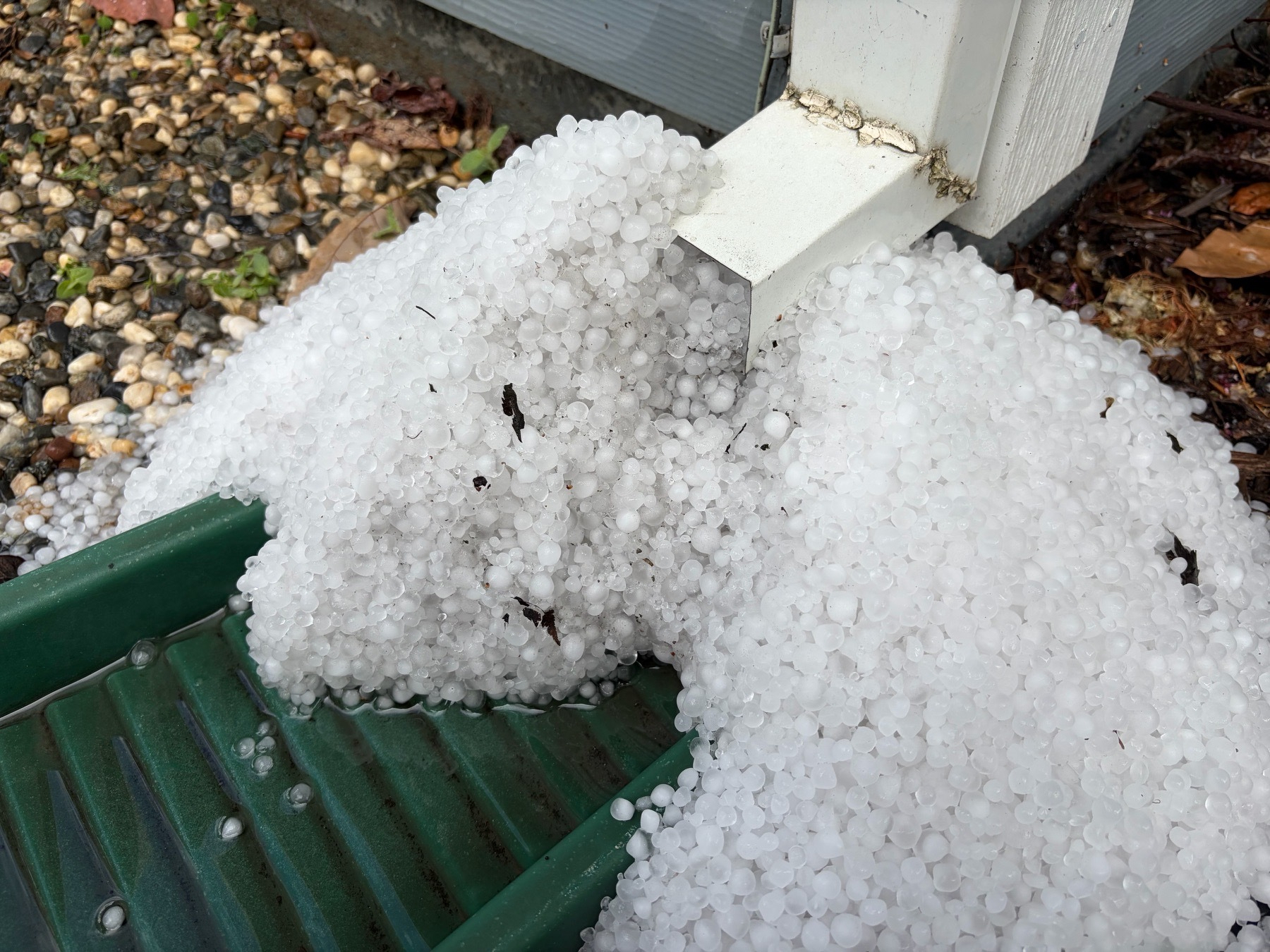Mound of hail that accumulated below a gutter down spout