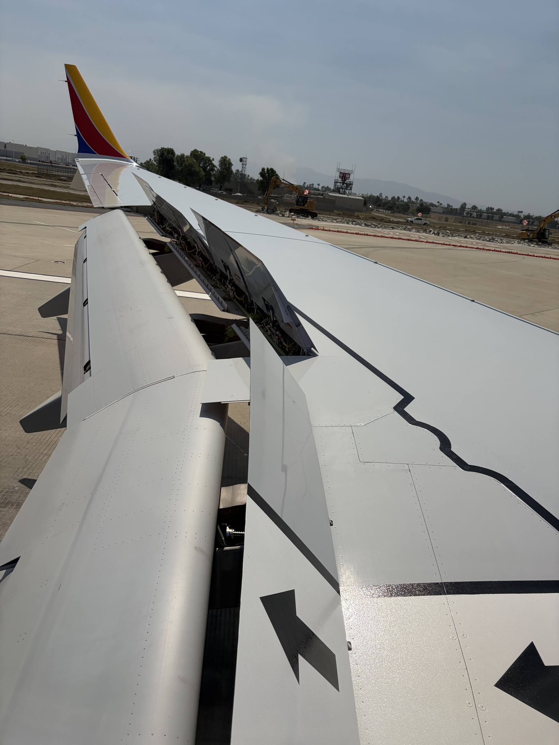 IMG_0310.jpeg Overwing view of a Southwest 737 Max 8 with speed brakes fully deployed when landing at Ontario, California. The brakes are not quite vertical and the flaps are probably around 30 degrees. It's a smoggy day in Ontario, CA.