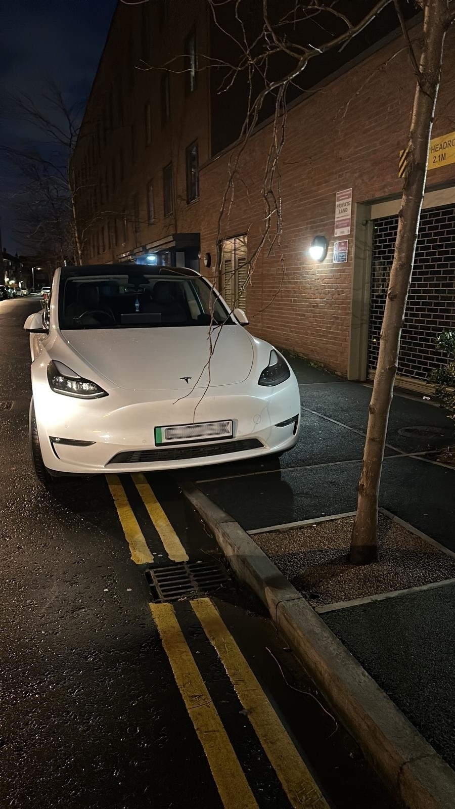An antisocially-parked white Tesla