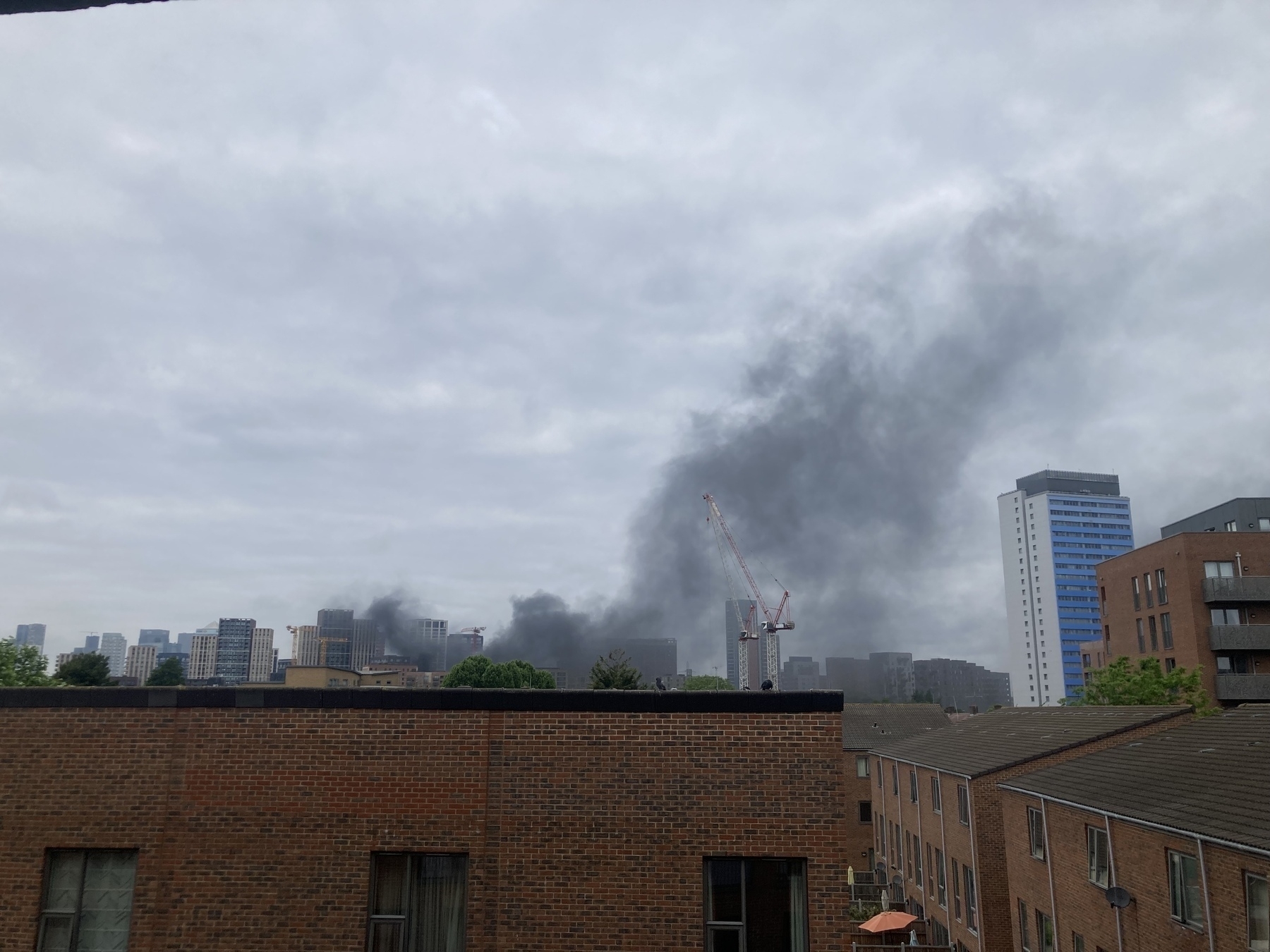 Smoke billows over the rooftops, obscuring construction and high rise buildings 